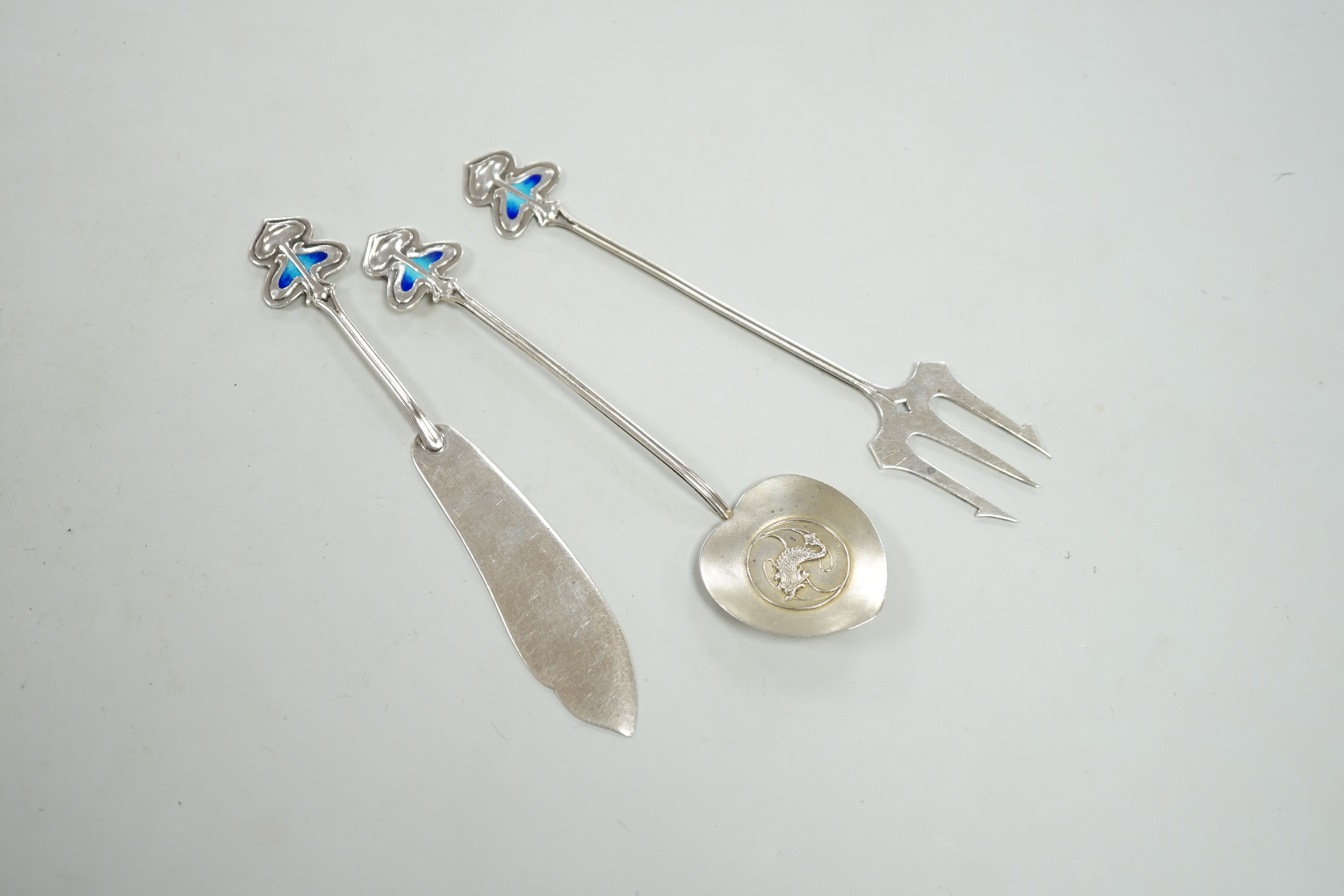 An Edwardian Art Nouveau silver and enamel, butter knife, pickle fork and small server, by Daniel George Collins, Birmingham, 1905, server 13.1cm.                                                                          