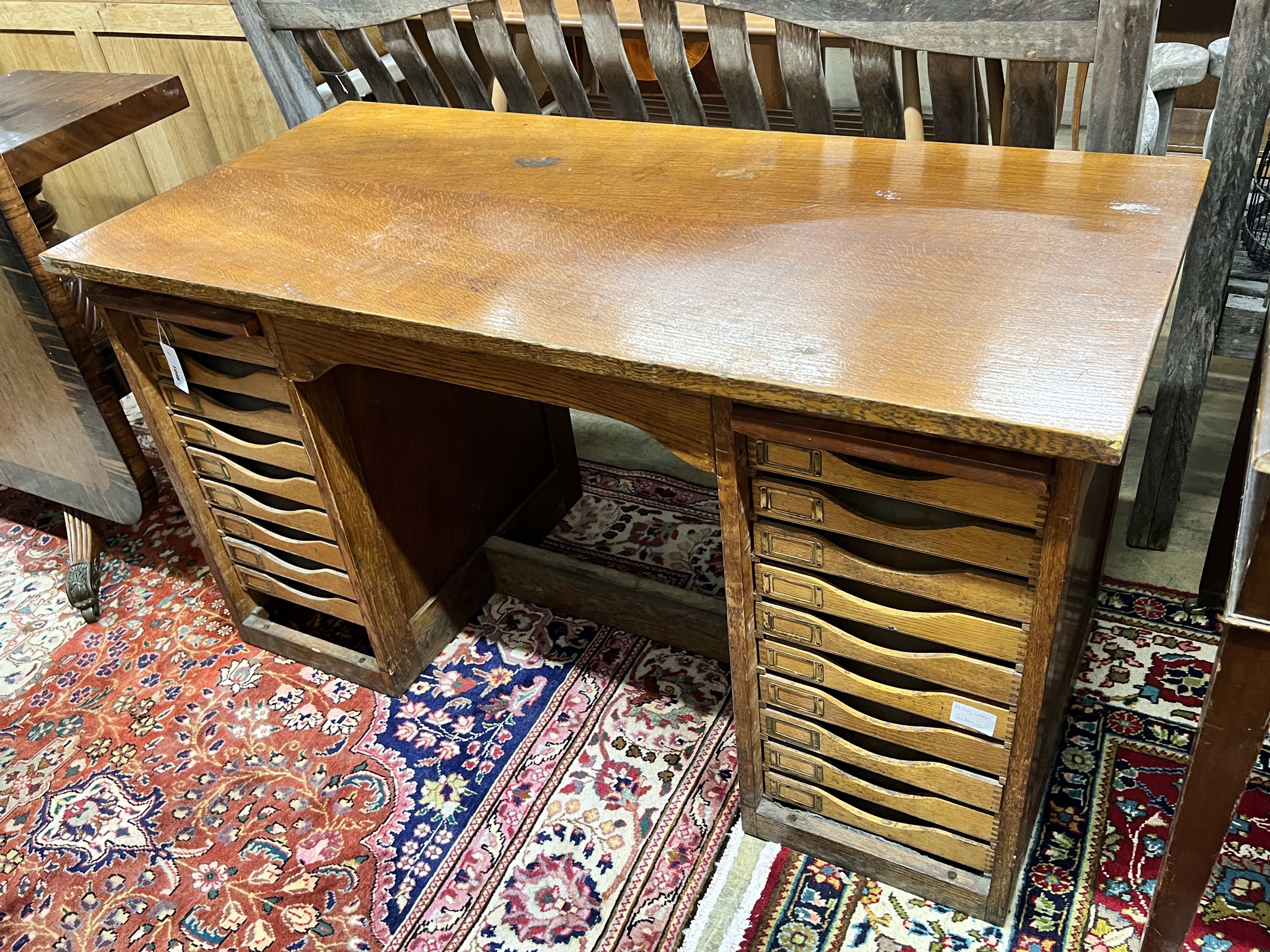 A mid 20th century oak kneehole desk fitted filing drawers, lacking tambour shutters, length 129cm, depth 61cm, height 71cm                                                                                                 