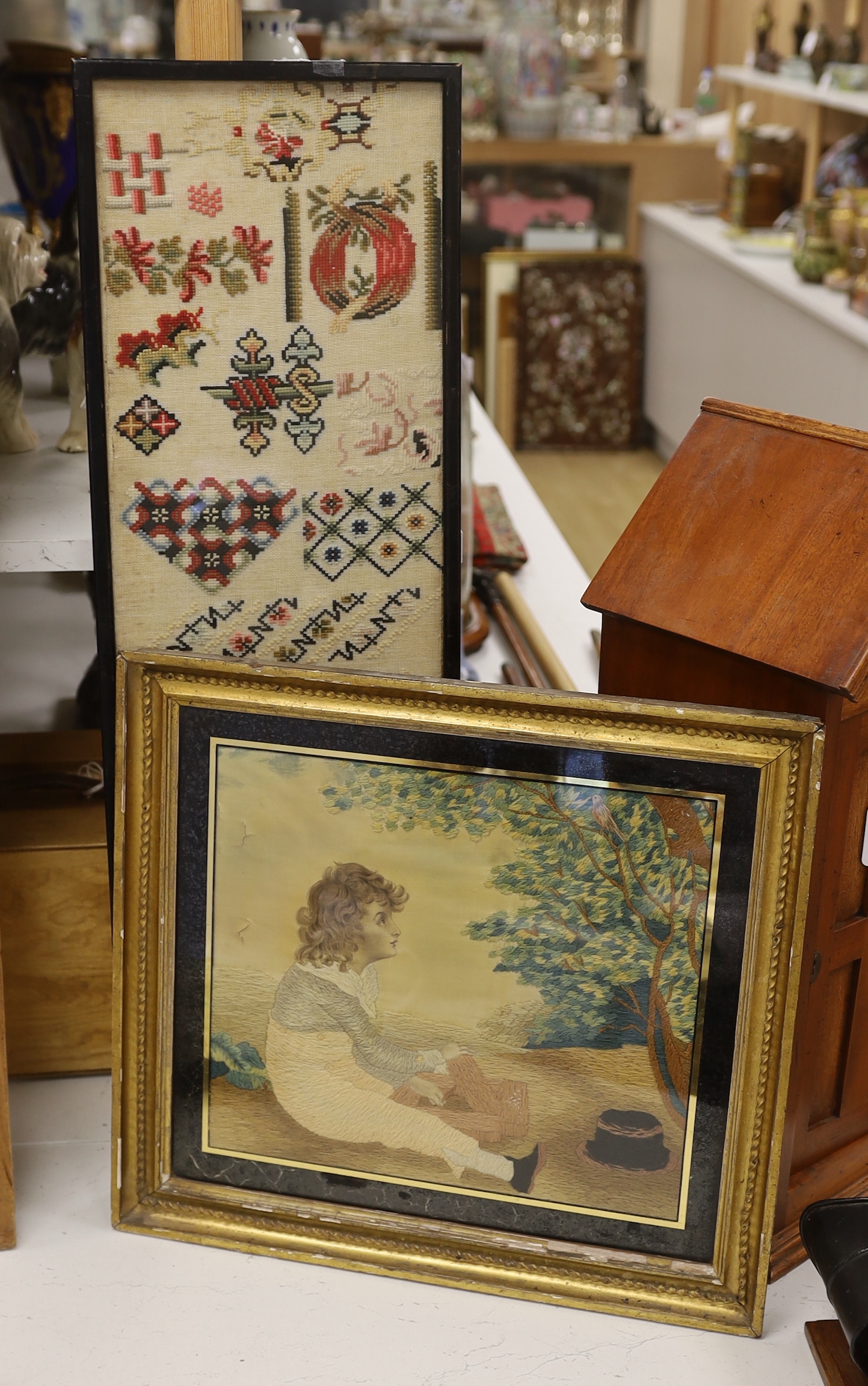 A Regency silk and wool embroidery of a seated boy by a tree and a Victorian spot motif wool-worked sampler, Regency embroidery 29.5cm x 33cm wide                                                                          