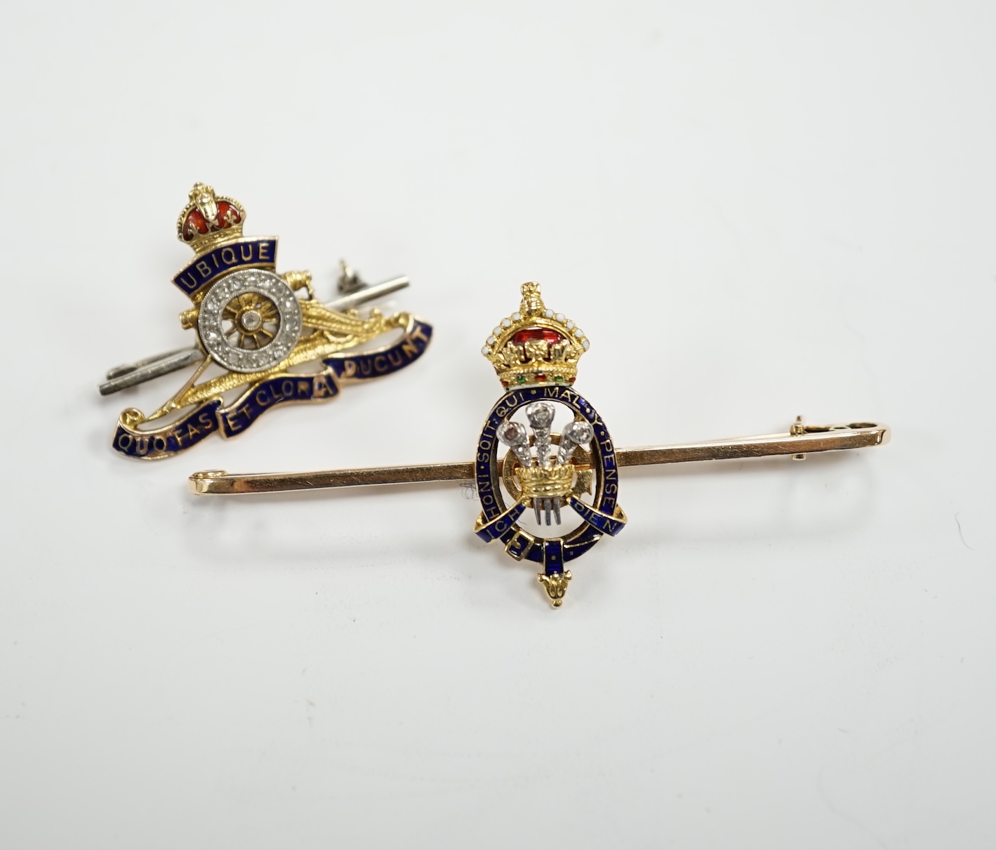 An Edwardian 15ct, enamel and rose cut diamond set Prince of Wales Order of The Garter insignia sweethearts bar brooch, 59mm and a similar yellow metal enamel and diamond chip set Royal Artillery sweethearts brooch, gros