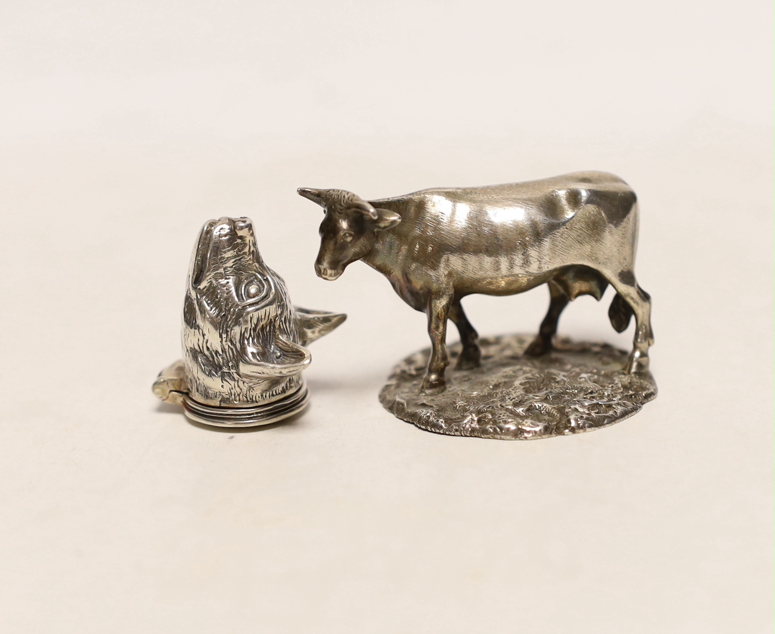 A mid Victorian silver model of a cow, on rustic circular base, Edward & John Barnard, London, circa 1860, length 55mm and a white metal small box modelled as a fox head, with hinged cover.                               