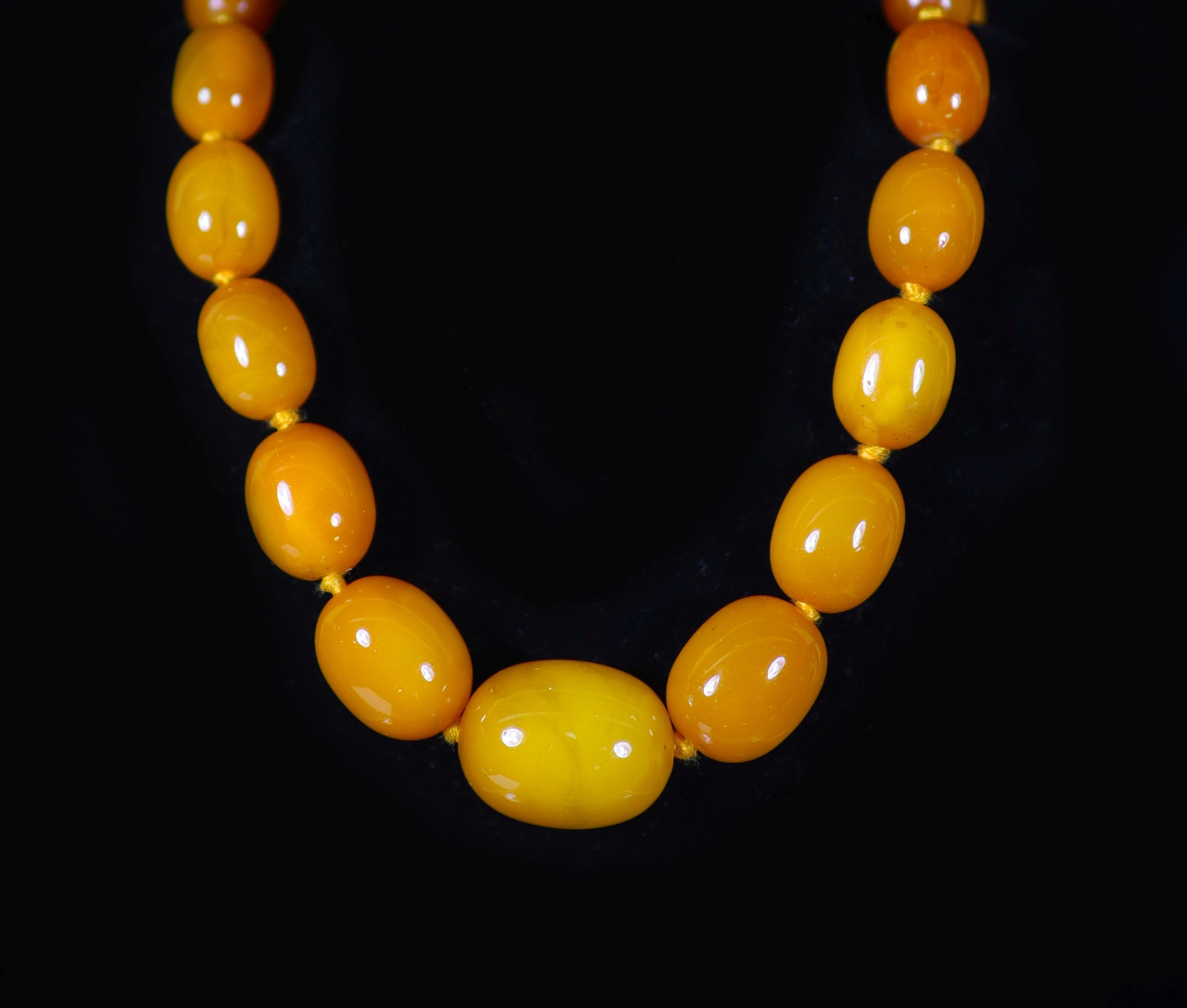 A single strand graduated oval amber bead necklace                                                                                                                                                                          