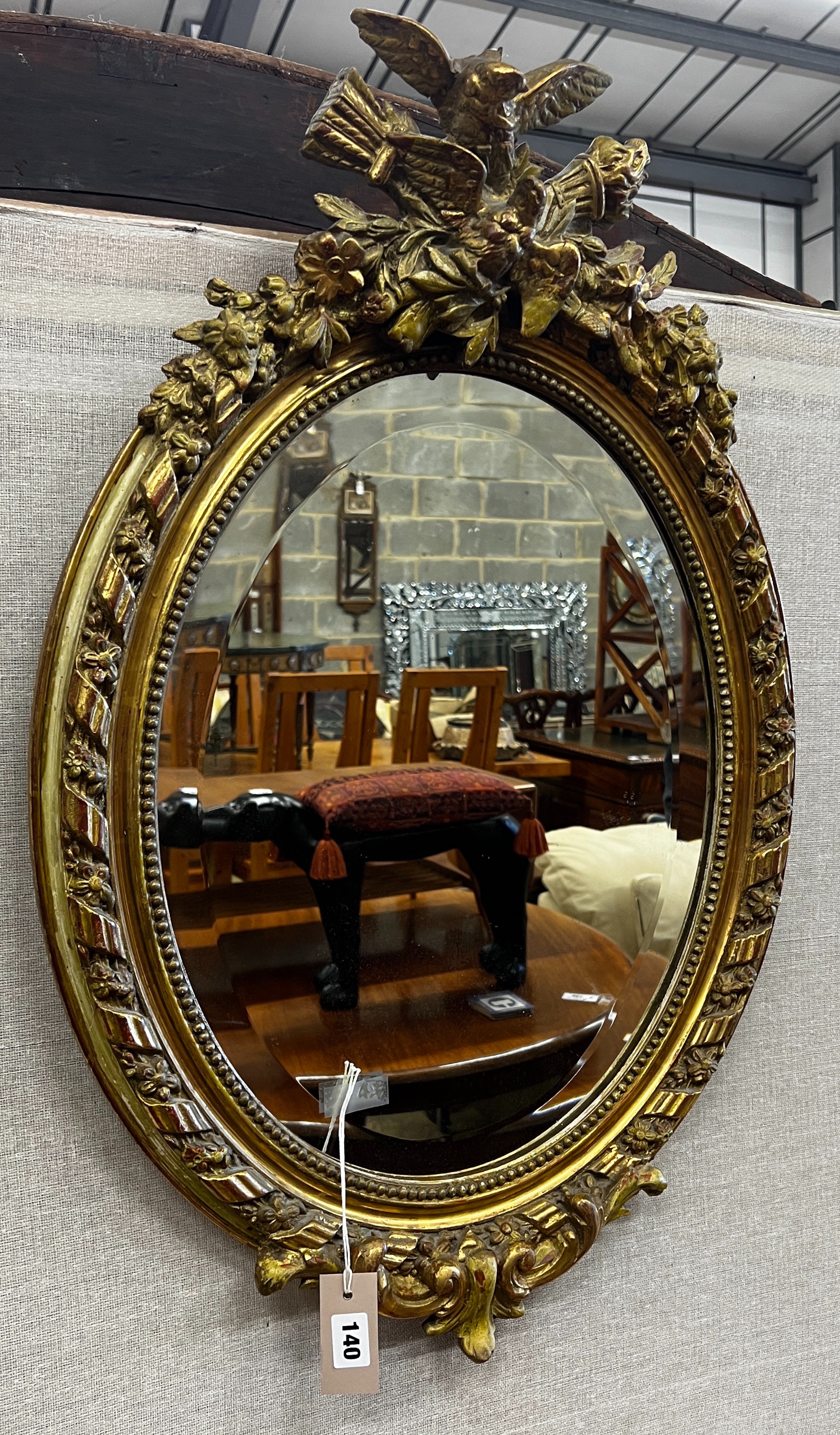 A 19th century French giltwood and composition oval wall mirror with pierced scrolling pediment, width 54cm, height 82cm                                                                                                    