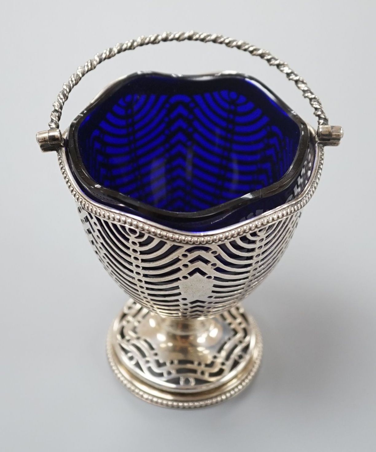 A George III pierced silver sugar basket, Burrage Davenport, London, 1777, with blue glass liner, height 96mm.                                                                                                              