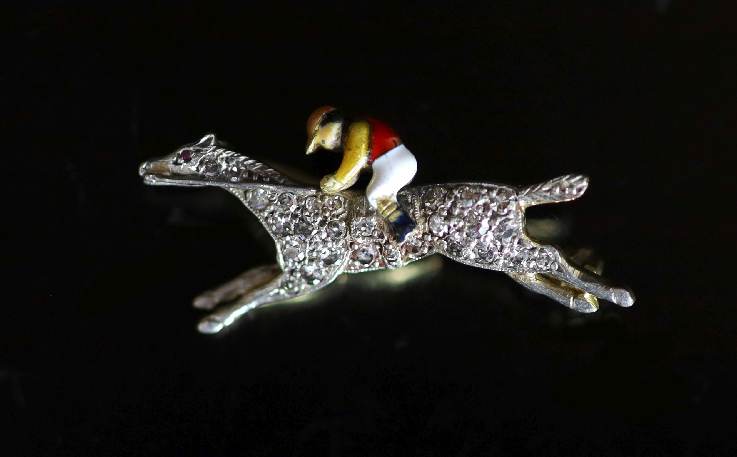 An early 20th century gold, diamond chip and enamel set 'horse and jockey' brooch                                                                                                                                           