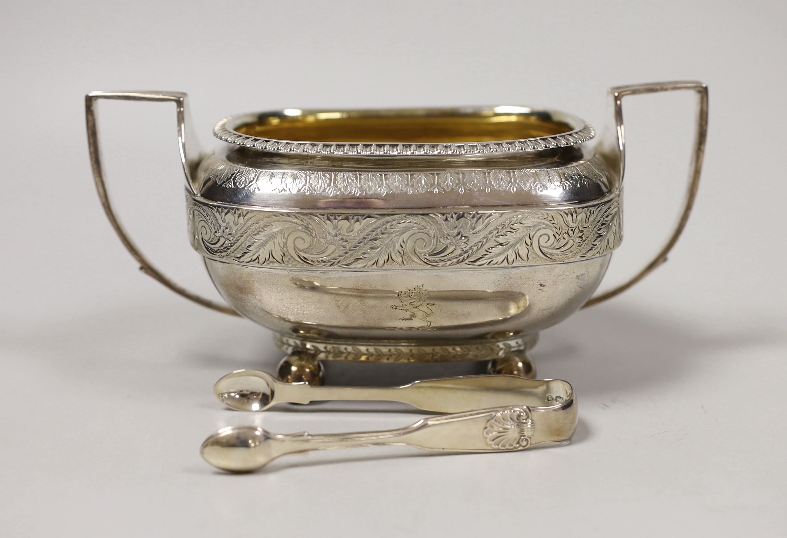 A George III engraved silver two handled sugar bowl, Emes & Barnard, London, 1811, overall width 18.5cm and a pair of Victorian silver sugar tongs, 10.4oz.                                                                 