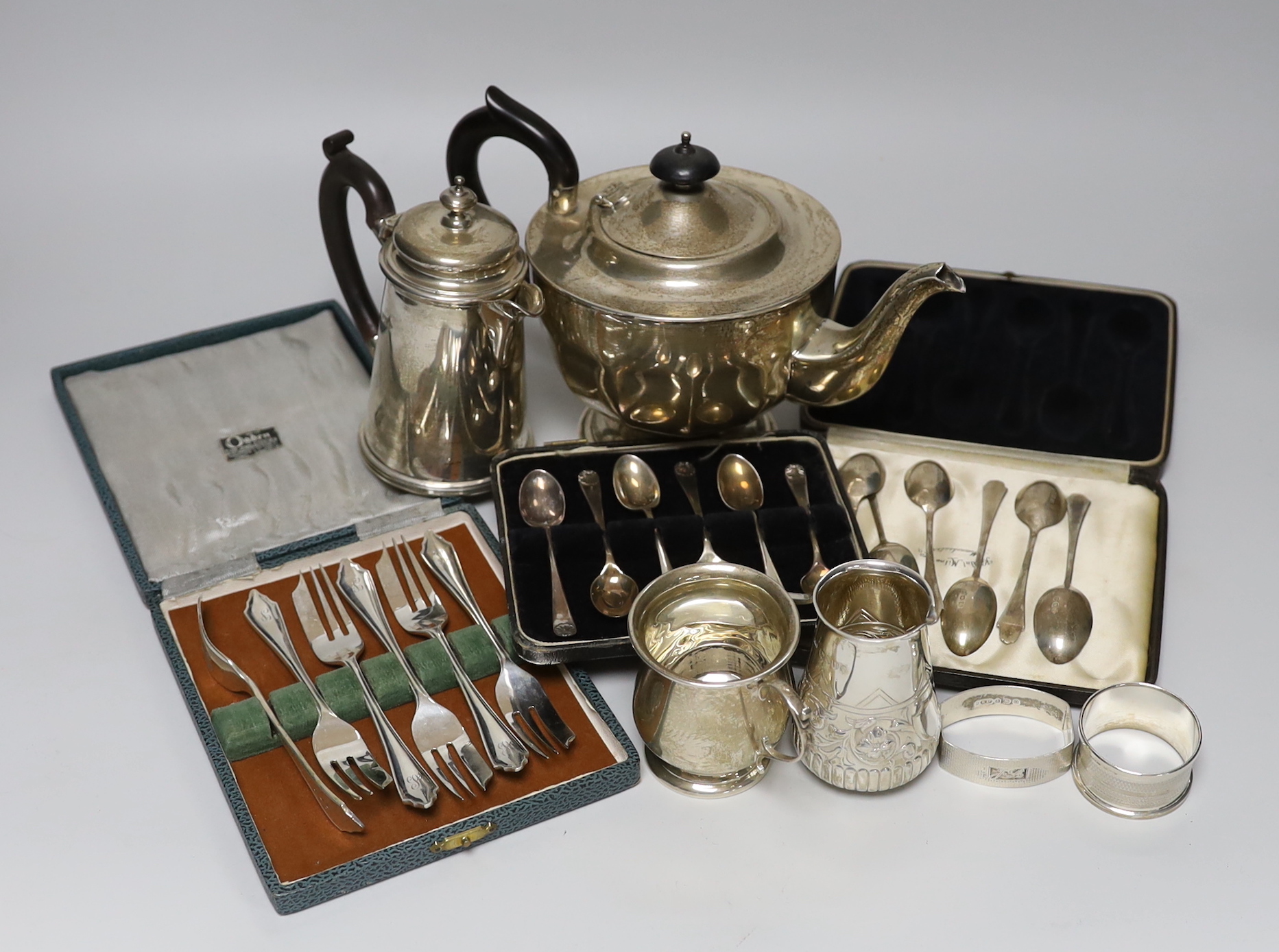 A mixed collection of silver items to include a George V teapot by Viners Ltd, a hot water pot, Victorian cream jug. christening mug, napkin rings and cased sets of teaspoons and pastry forks.                            