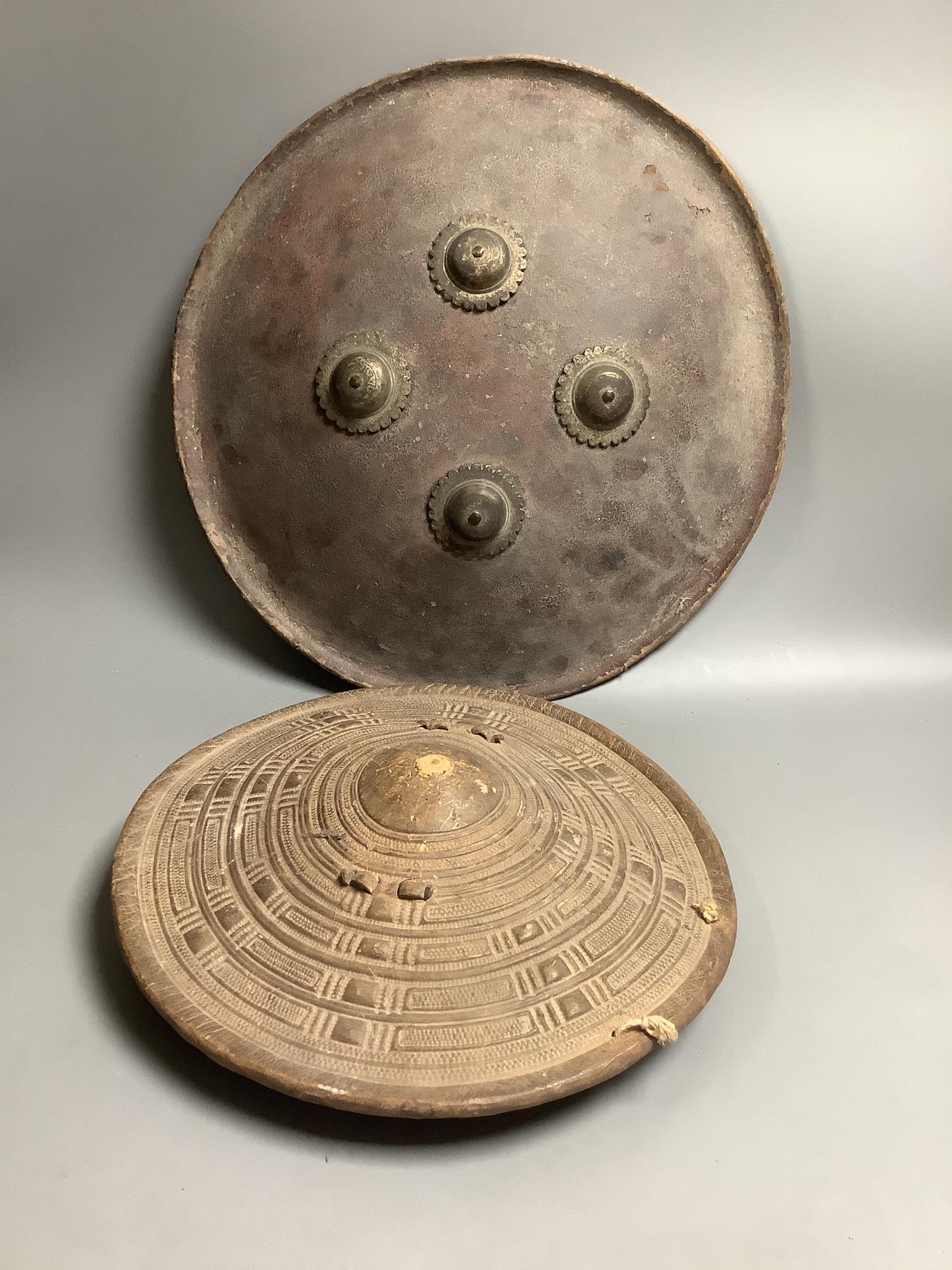 A 19th century Indo-Persian animal hide dahl shield, 41cm diameter, and an African rhino hide shield                                                                                                                        