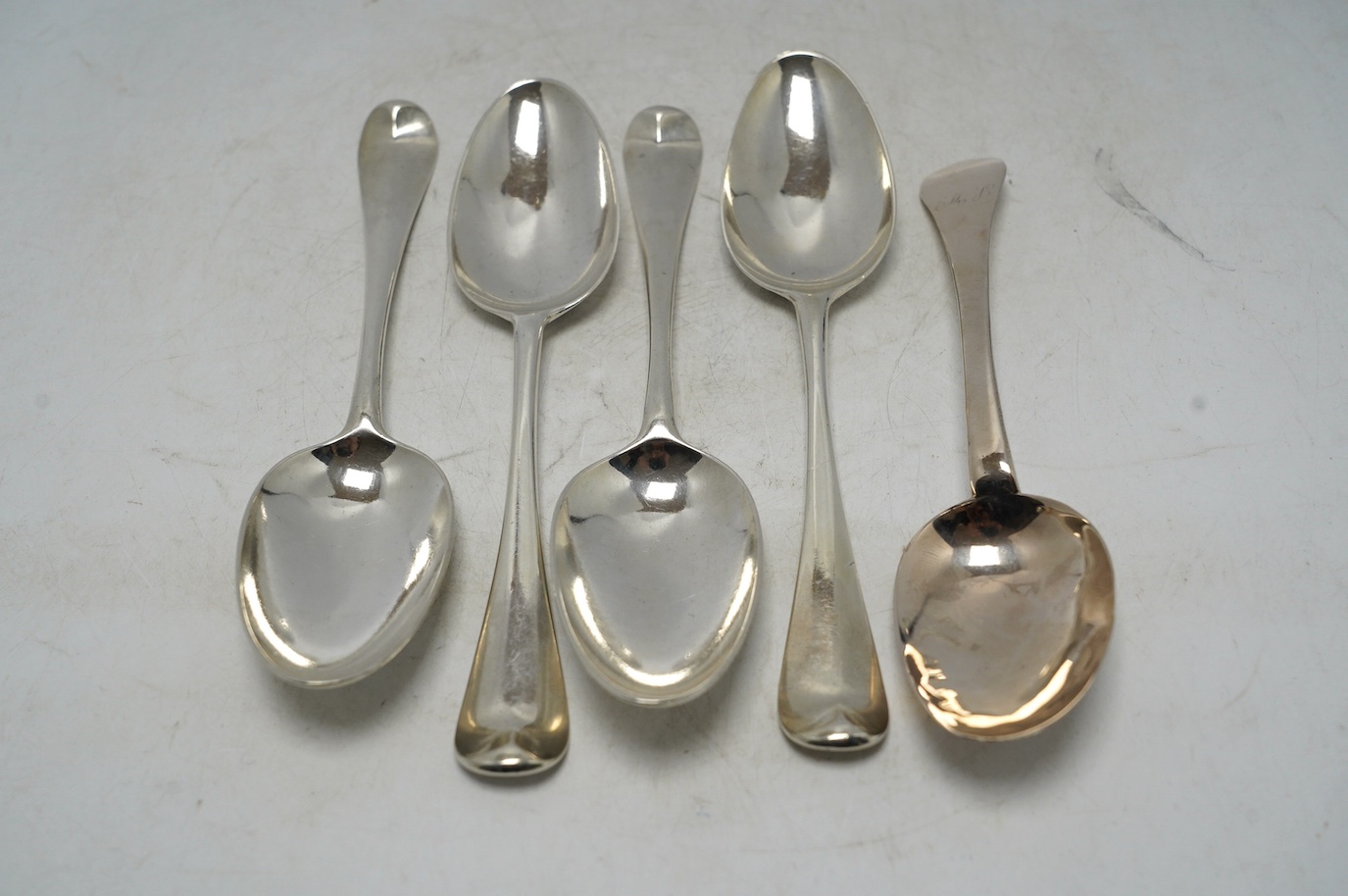 An early 18th century? silver dog nose spoon, indistinct marks, 19.2cm, together with a set of four George II silver table spoons, with lace back bowls, by William Turner, London, 1755, 10.6oz. Condition - poor to fair  