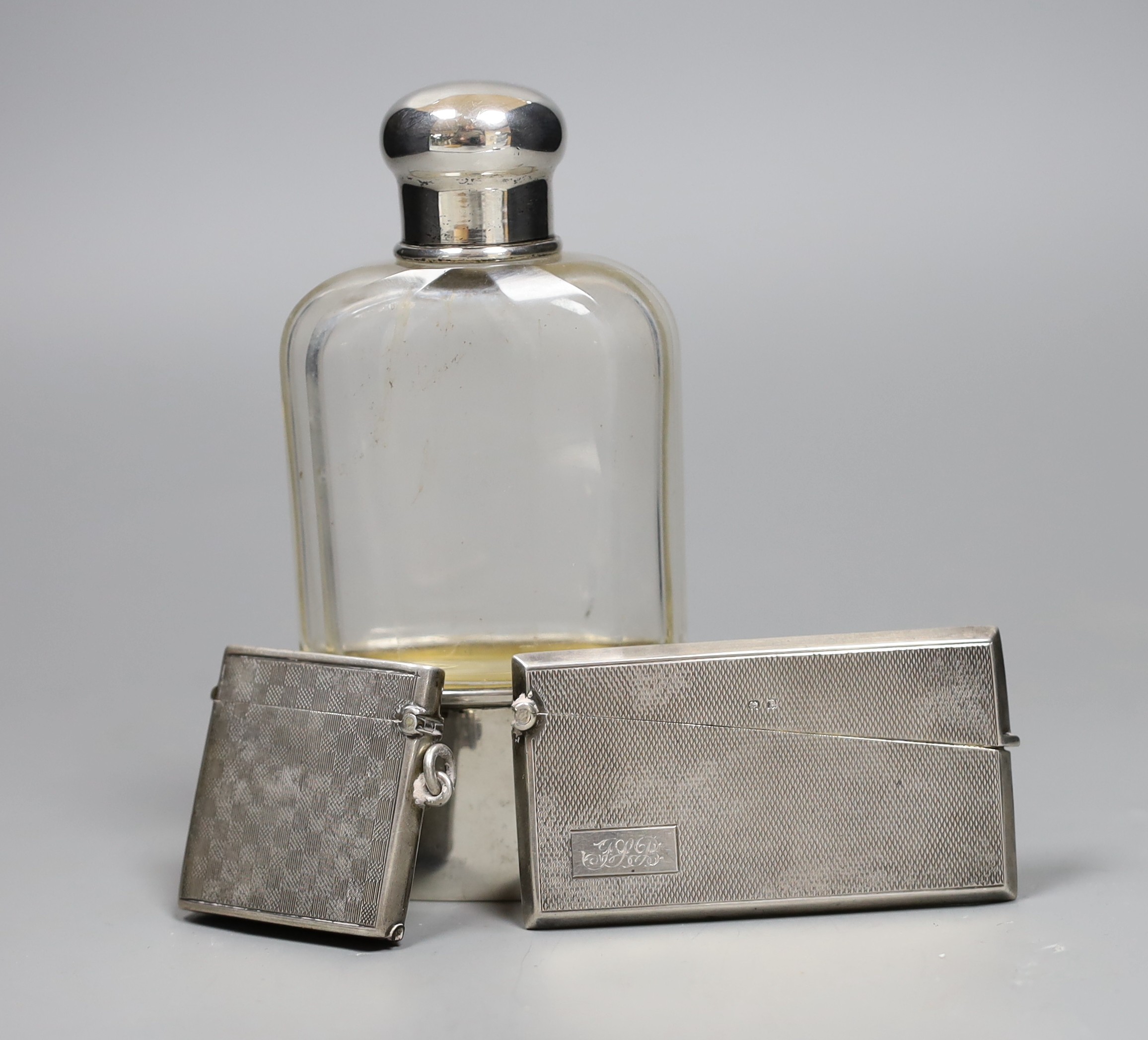 A German 800 standard white metal mounted glass hip flask, 14cm, a George V silver vesta case and a 1920's engine turned silver card case.                                                                                  