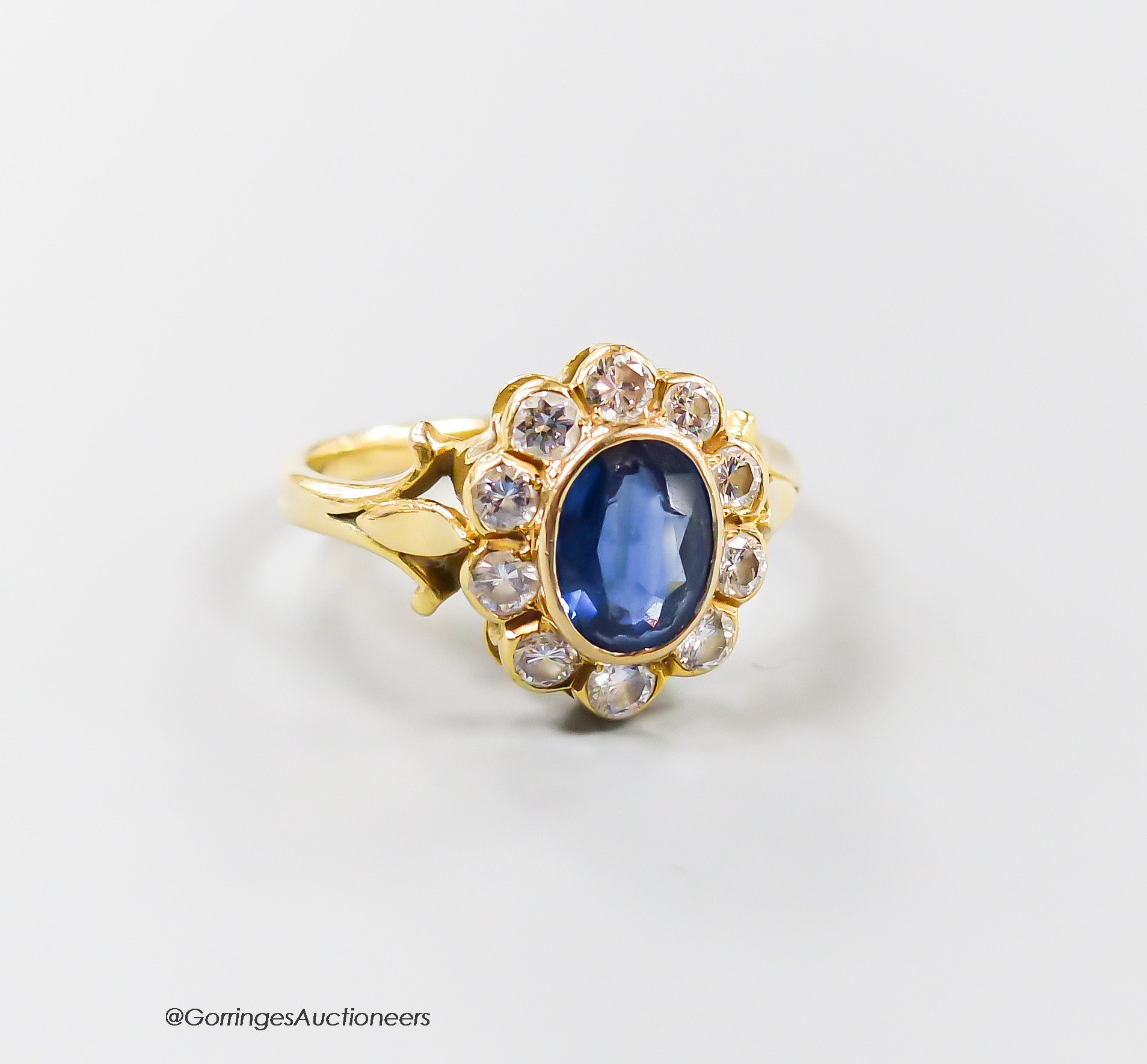 A modern 18ct gold, sapphire and diamond set oval cluster ring, size N, gross 3.8 grams.                                                                                                                                    