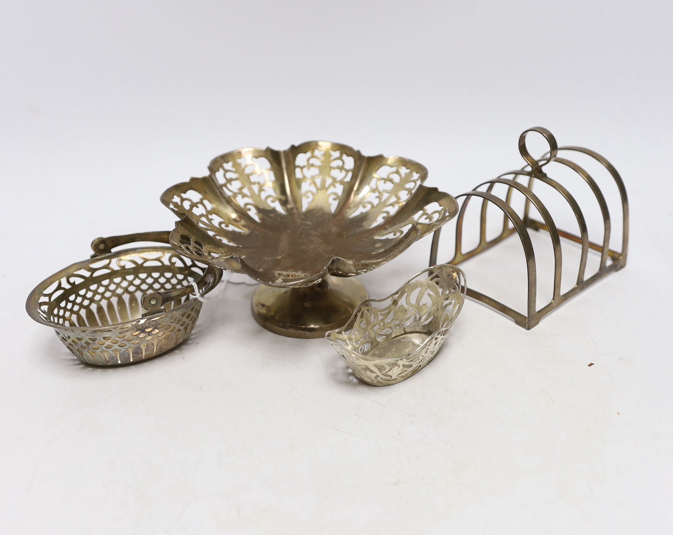 A small silver basket, a pierced silver pedestal dish, a George V silver five bar toast rack and a pierced silver bonbon dish, 10.2oz.                                                                                      