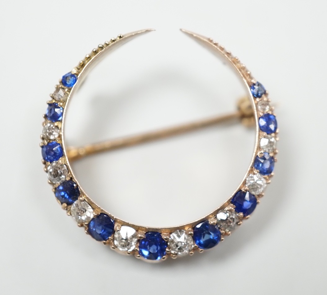 An Edwardian yellow metal, graduated sapphire and diamond set crescent brooch, 22mm, gross weight 3 grams.                                                                                                                  