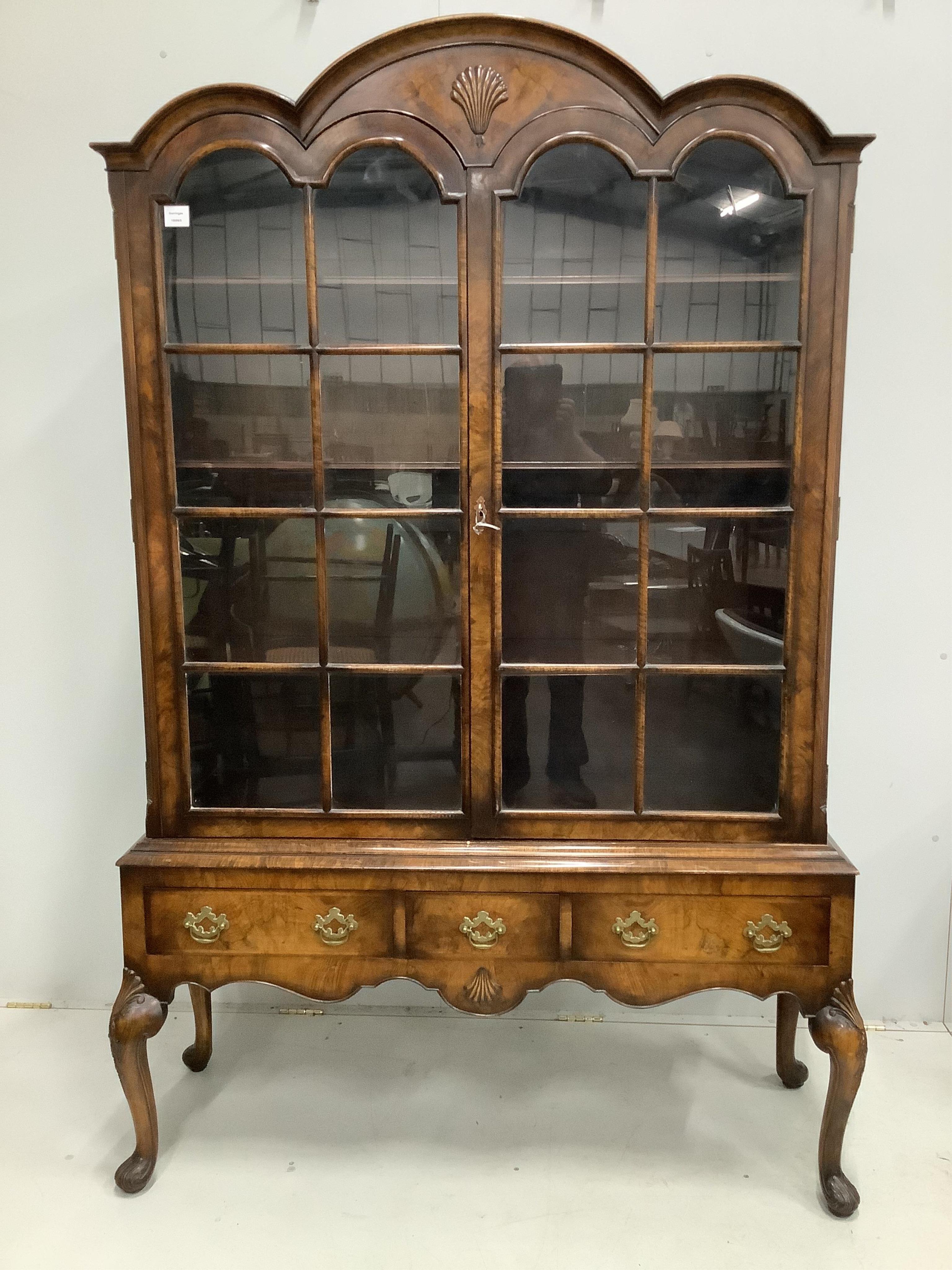 A 1930's Queen Anne Revival figured walnut bookcase, width 136cm, height 205cm. Condition - good                                                                                                                            