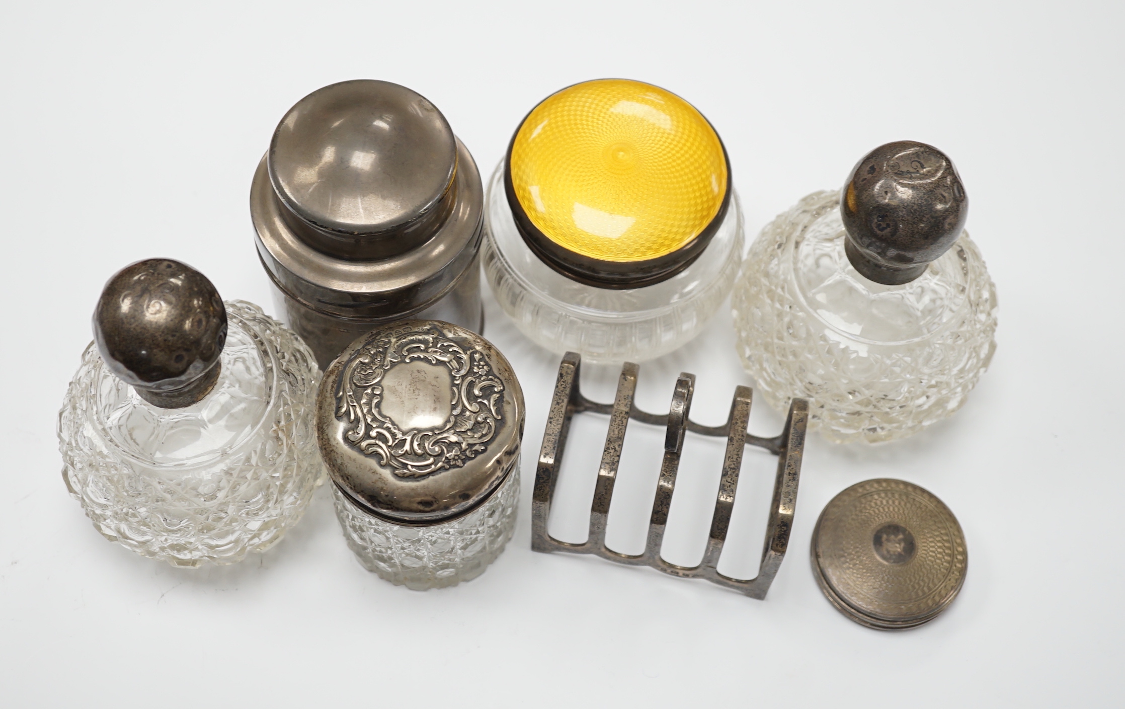 A George V silver tea? cannister, by Mappin & Webb, five silver mounted dressing accessories and a silver toast rack                                                                                                        