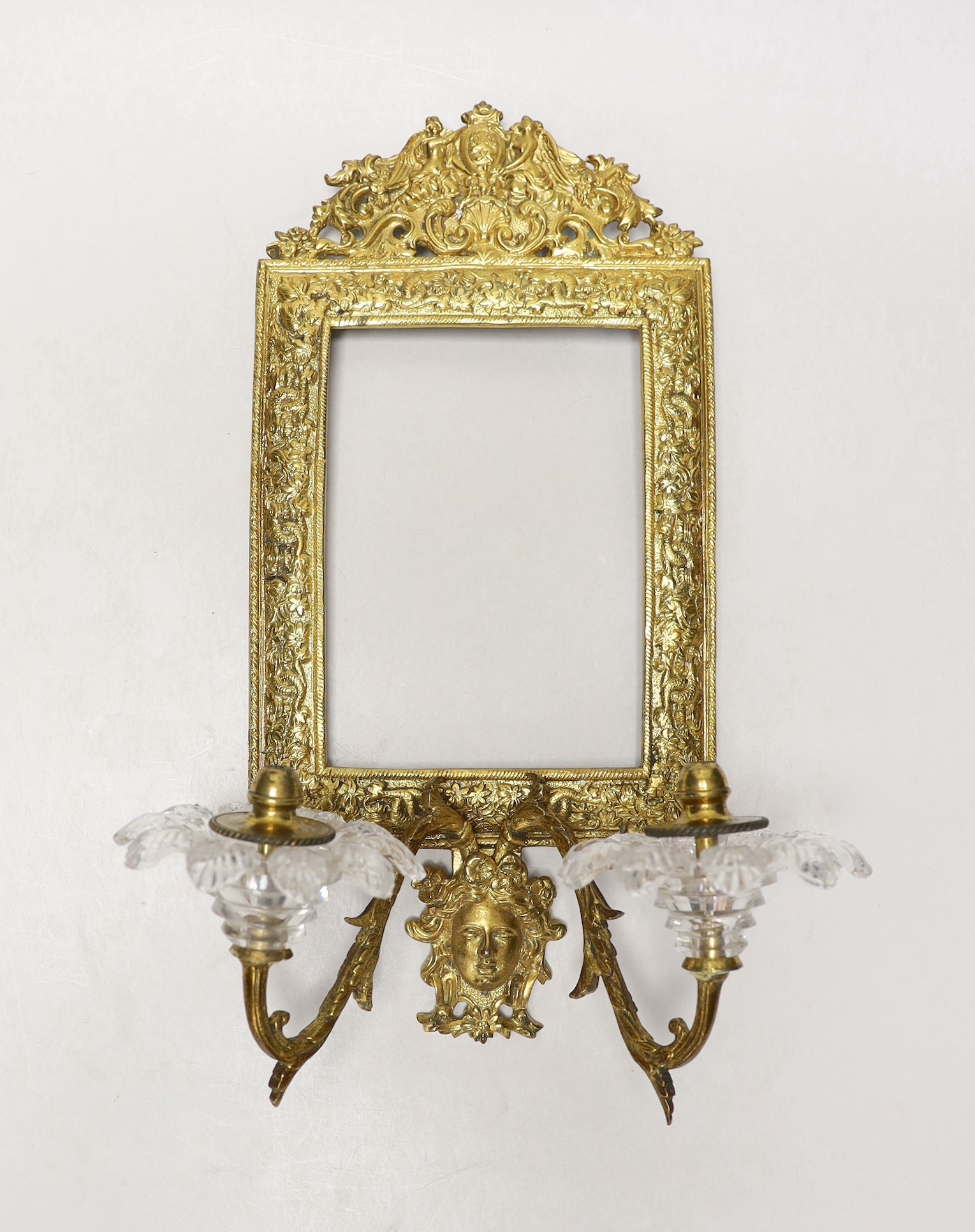A decorative two branch ormolu wall mirror, lacking the mirror inset. 39cm tall overall, 16.5 x 11.5cm                                                                                                                      
