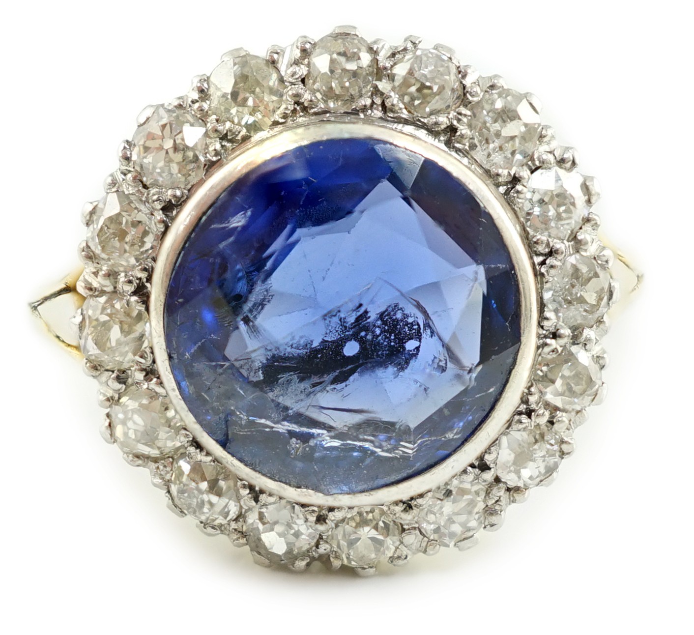 A gold and single stone round cut sapphire set dress ring, with diamond set border                                                                                                                                          