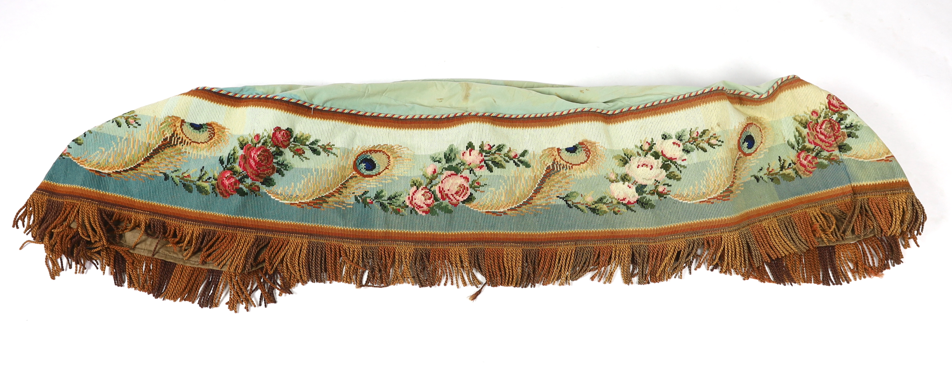 A 19th century Berlin hand wool worked floral and peacock feather designed border, with a deep fringe and cording along the top edge, used as the outer edge/border to a plain cotton turquoise table cover, the wool work a