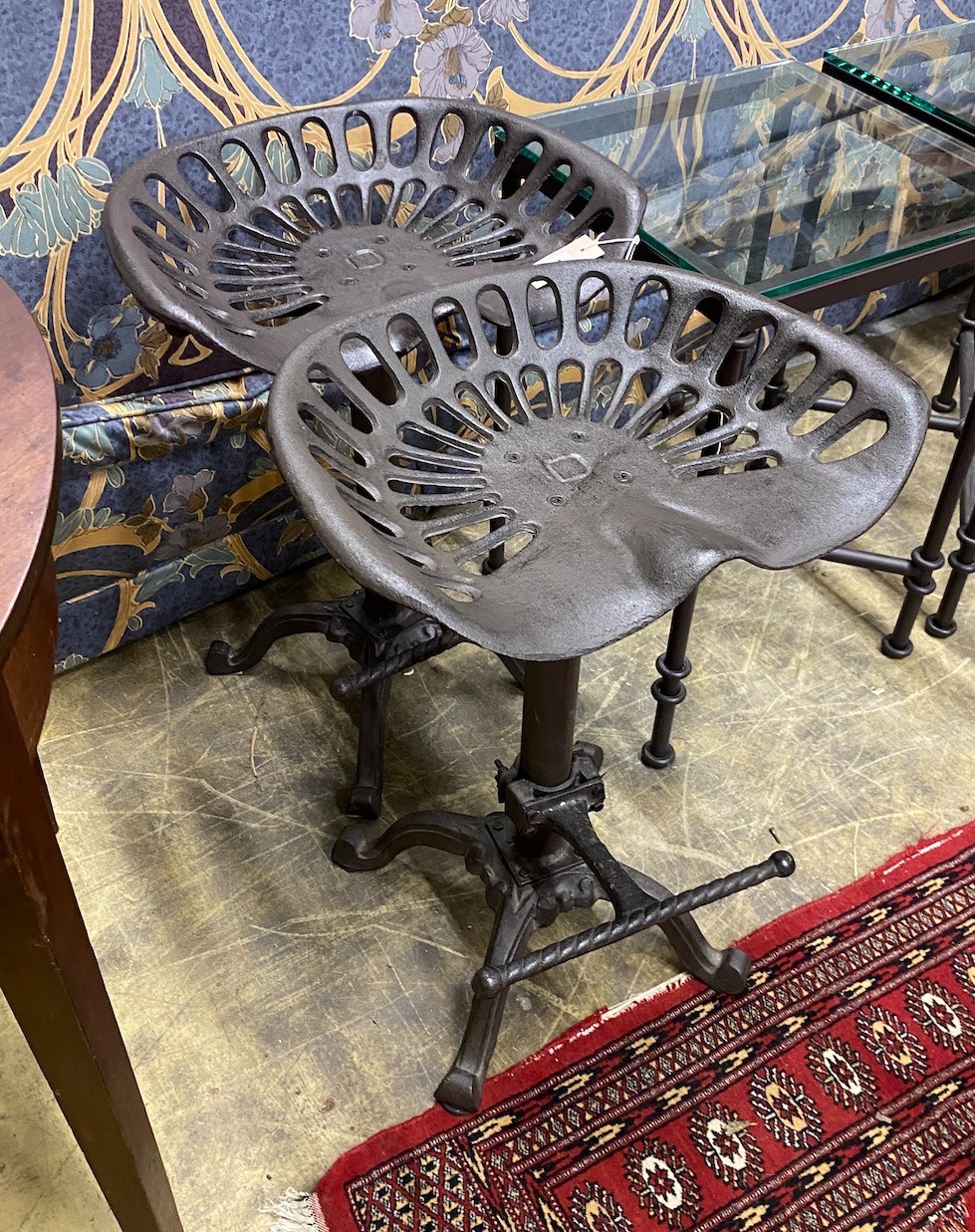 A pair of cast iron tractor seat stools, width 46cm, height 65cm                                                                                                                                                            