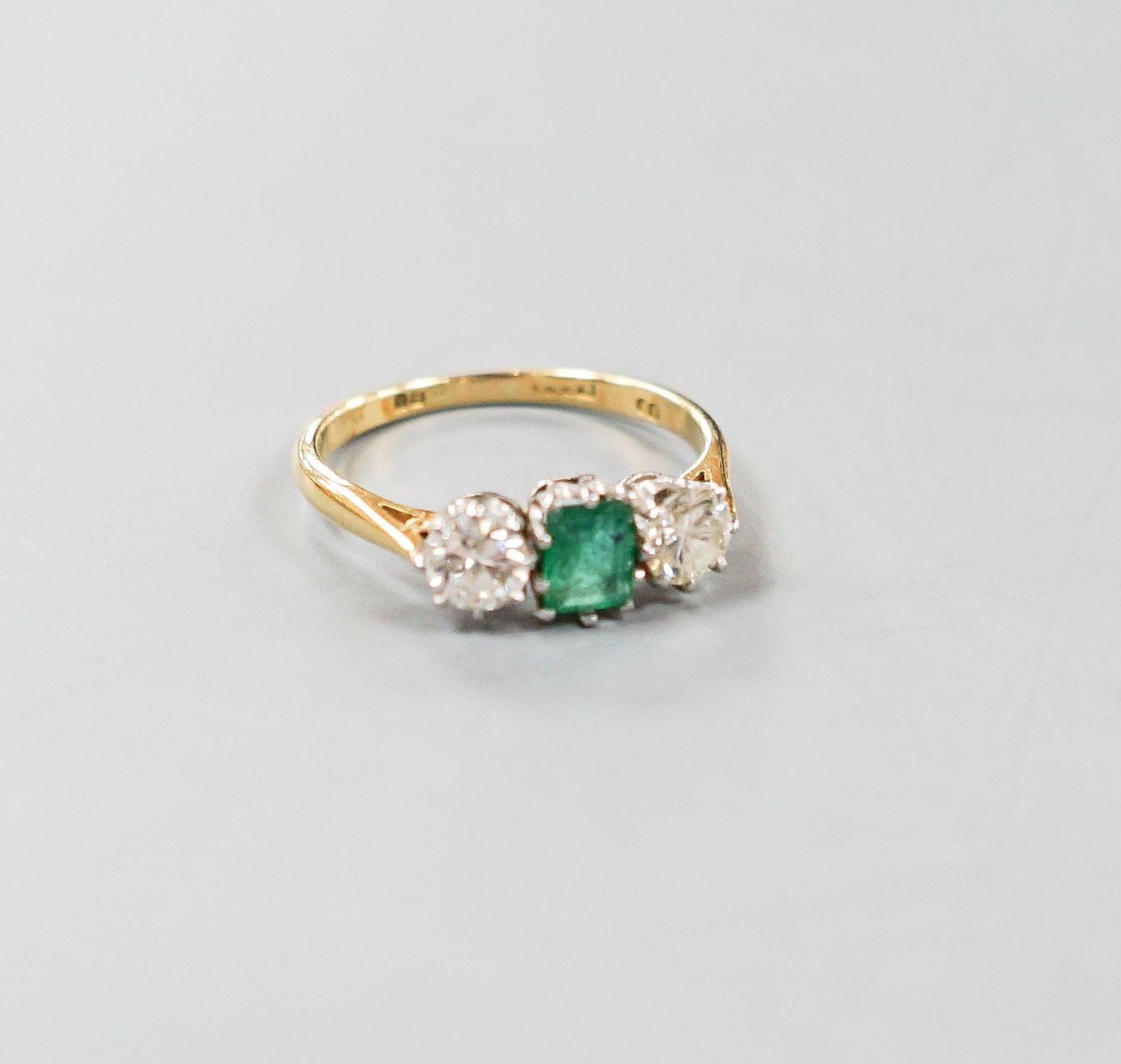 A modern 18ct gold, emerald and diamond set three stone ring, size O, gross weight 3.1 grams.                                                                                                                               