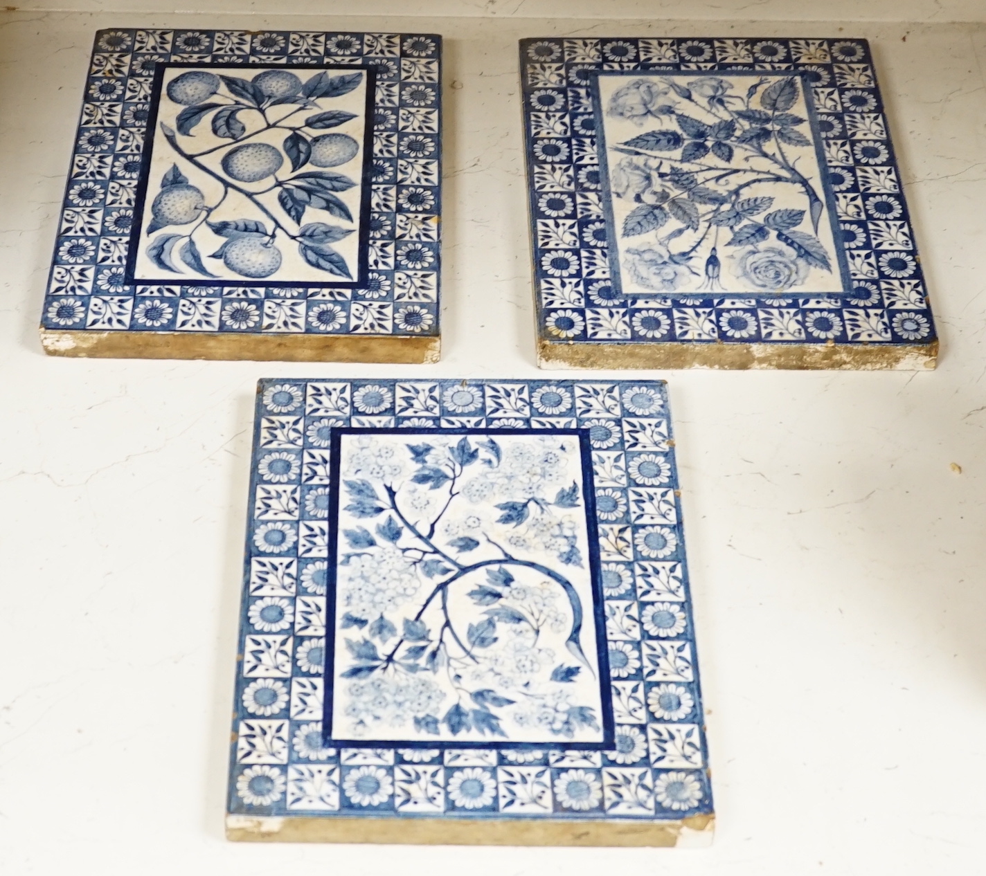 Three Victorian blue and white Mintons tiles decorated with flowers and fruit, each stamped to the base, each 29cm x 22cm                                                                                                   