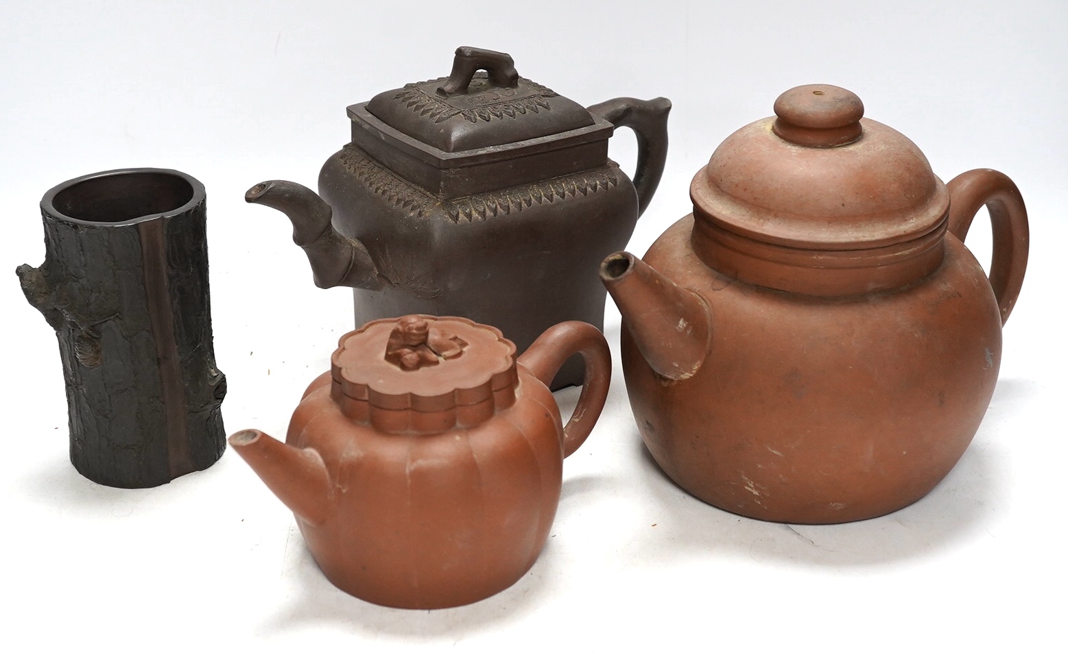 A 19th century Chinese Yixing pottery ‘tree trunk’ brush pot and three similar teapots, tallest 15cm. Condition - fair to good                                                                                              