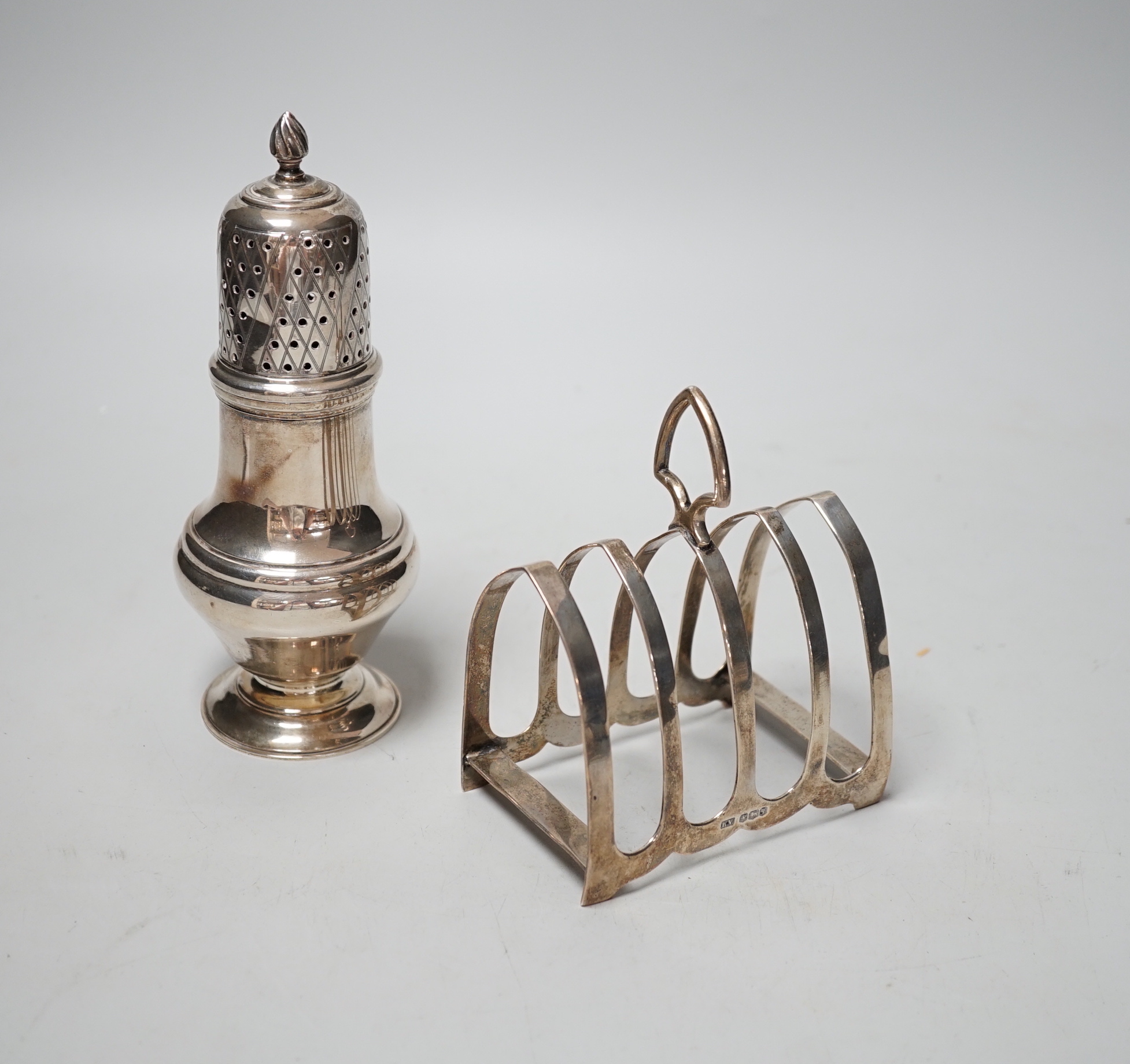 A modern silver sugar caster, 16.5cm and a George V silver toast rack, 8.7oz.                                                                                                                                               