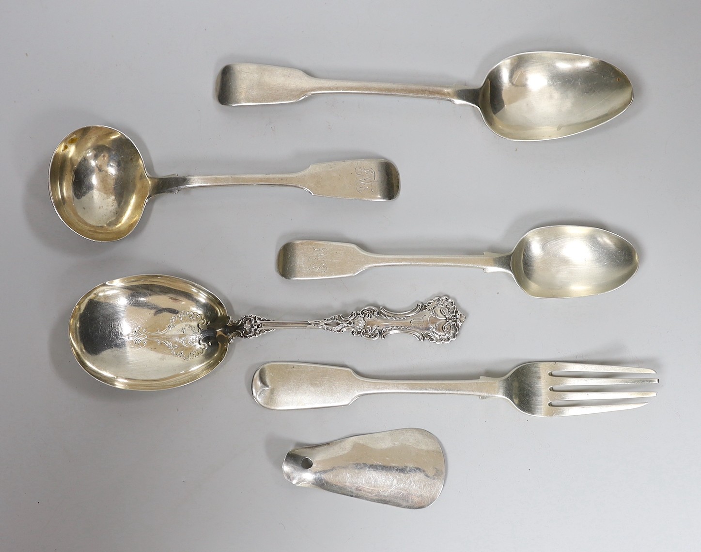 Four assorted items of silver flatware, a sterling serving spoon and a George V silver shoe horn (lacking ring), 10.6oz.                                                                                                    