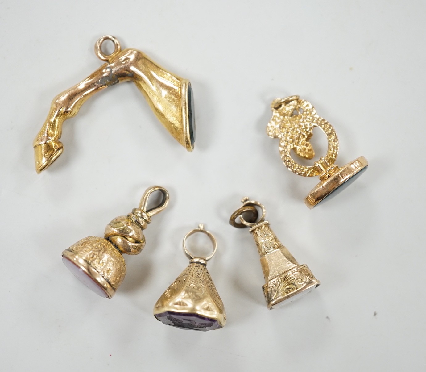 A Victorian yellow metal overlaid and bloodstone set fob seal, modelled as an entwined serpent, 22mm, two other similar fob seals set with chalcedony an a similar fob seal set with bloodstone and modelled as the leg of a