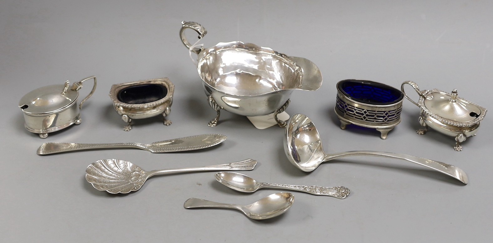 A George V silver sauce boat, Chester 1911, together with four silver condiments, a Georgian silver sauce ladle by William Bateman and four other items of silver cutlery.                                                  