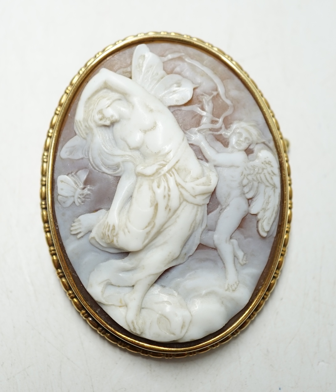 A continental yellow metal mounted oval cameo shell brooch, carved with fairies, 47mm, gross weight 11.6 grams. Condition - fair                                                                                            