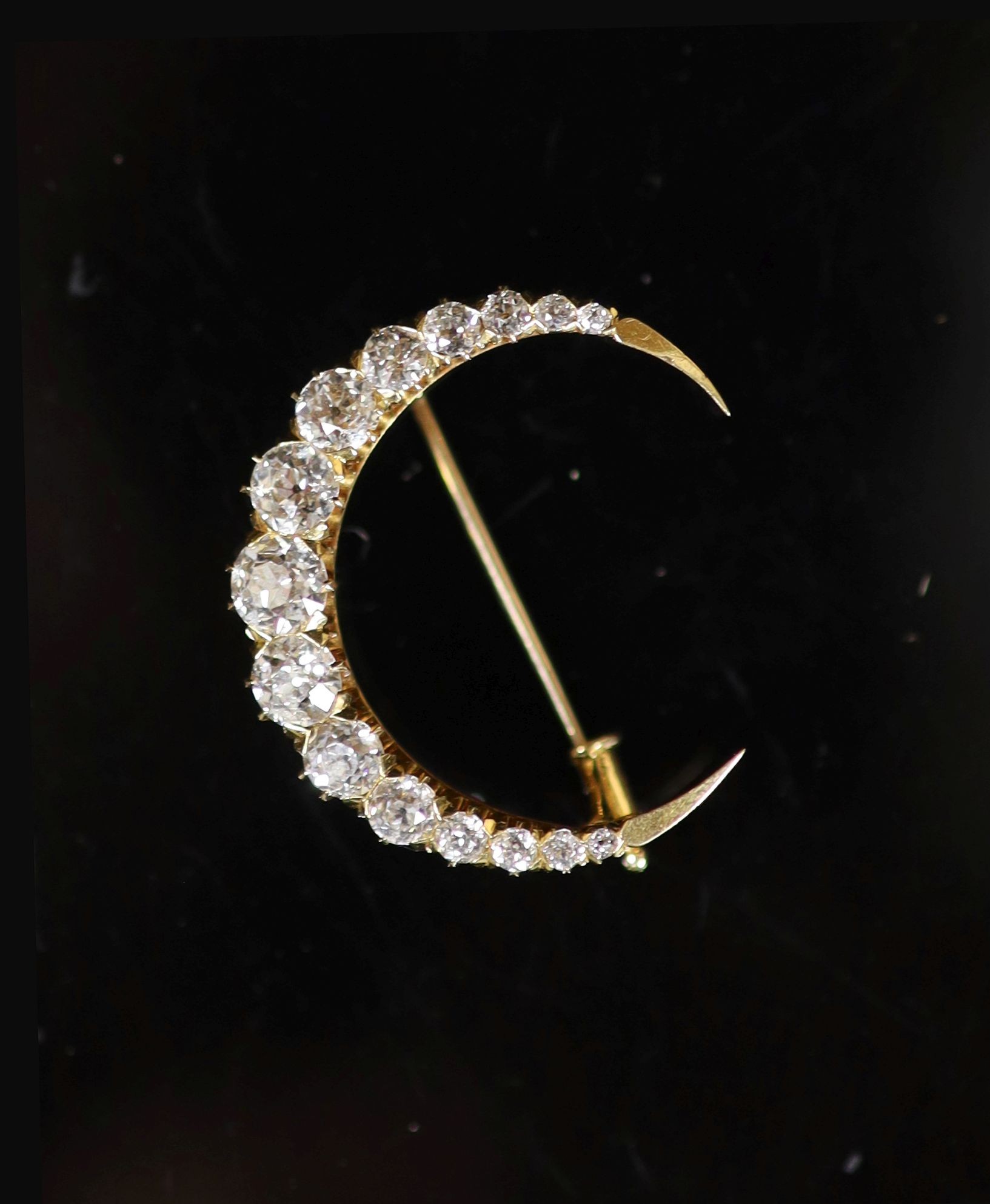 A gold and graduated fifteen stone old round cut diamond set crescent pendant brooch                                                                                                                                        