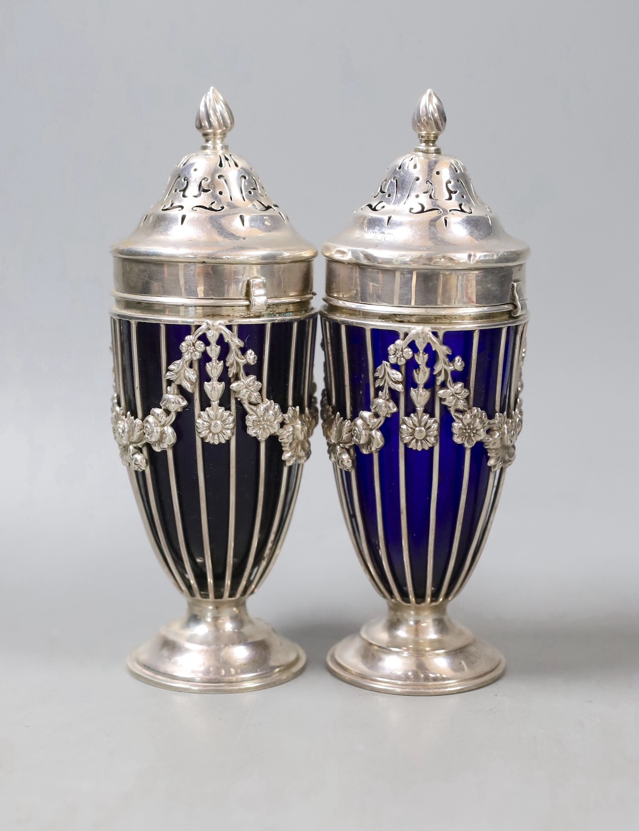 A pair of George V pierced silver sugar sifters, with blue glass liners, London, 1912, height 17.9cm.                                                                                                                       