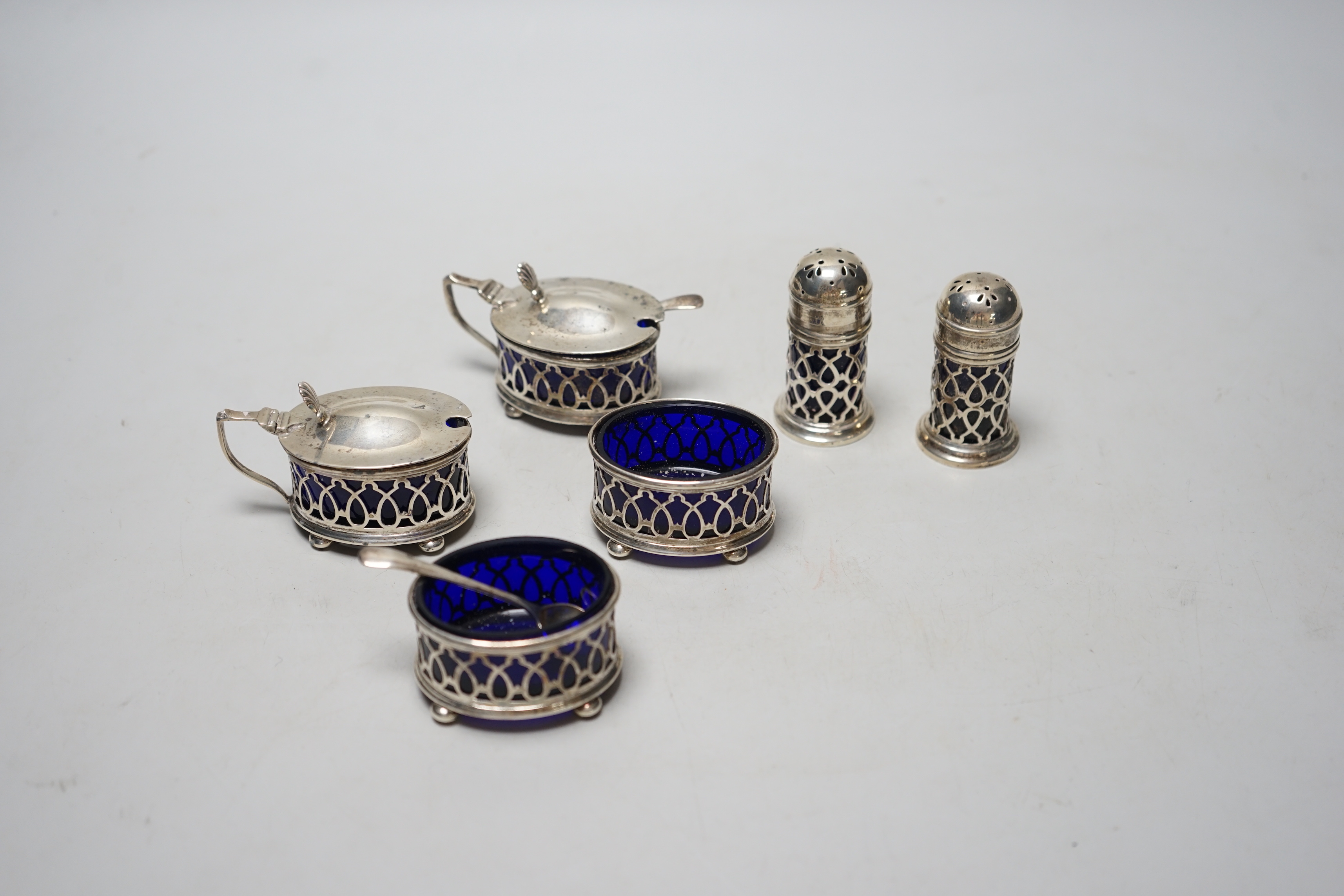 A George V pierced silver six piece condiment set, with blue glass liners, Gorham Manufacturing Co, Birmingham, 1919/21.                                                                                                    