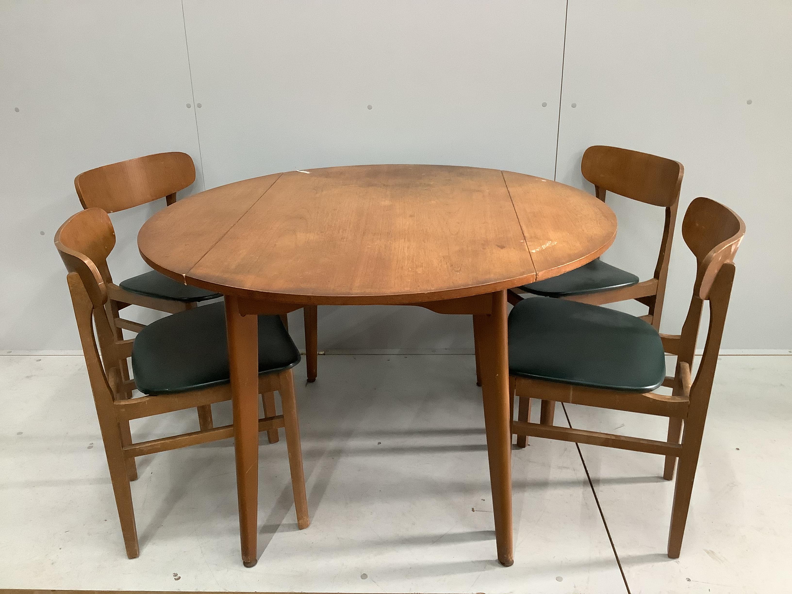 A mid century teak circular drop leaf dining table, diameter 114cm extended, height 73cm and four chairs                                                                                                                    