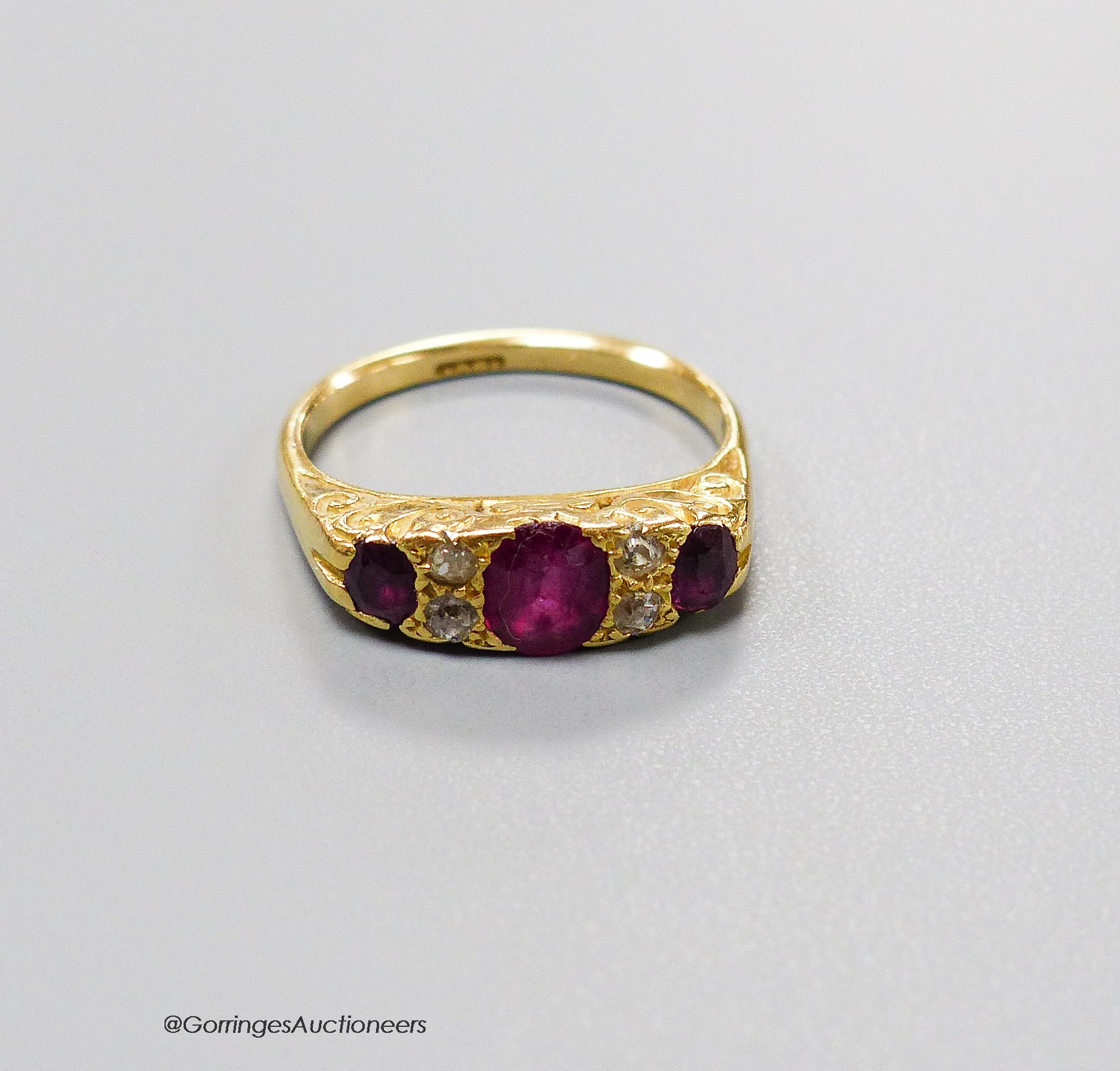 An early 20th century 18ct, three stone ruby and four stone diamond chip set half hoop ring, size L, gross 4.1 grams.                                                                                                       