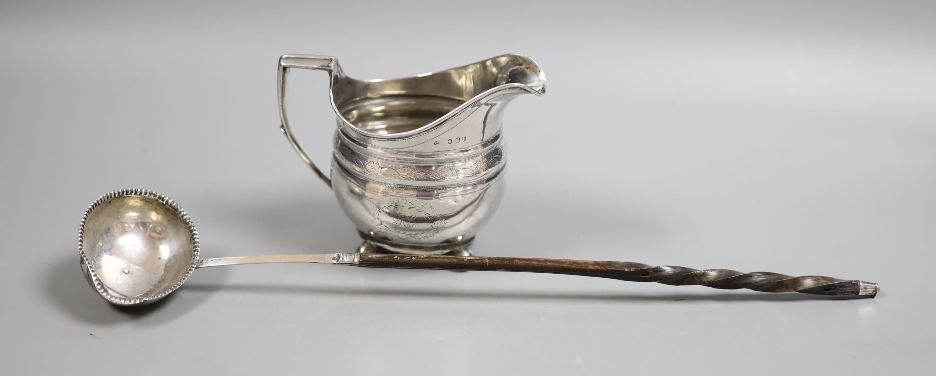 A George III silver cream jug, marks rubbed, height 10.7cm, and a 19th century toddy ladle.                                                                                                                                 