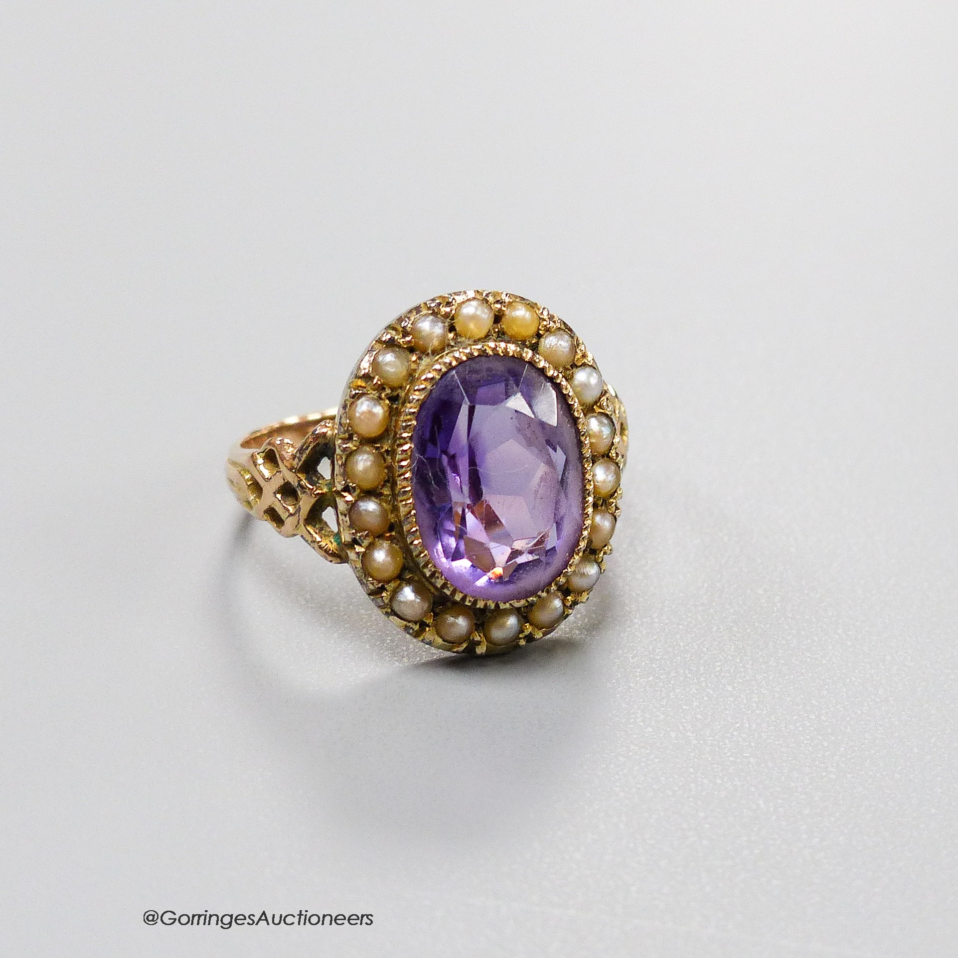 A 19th century yellow metal, amethyst and seed pearl set oval cluster dress ring, size N, gross 3.8 grams.                                                                                                                  