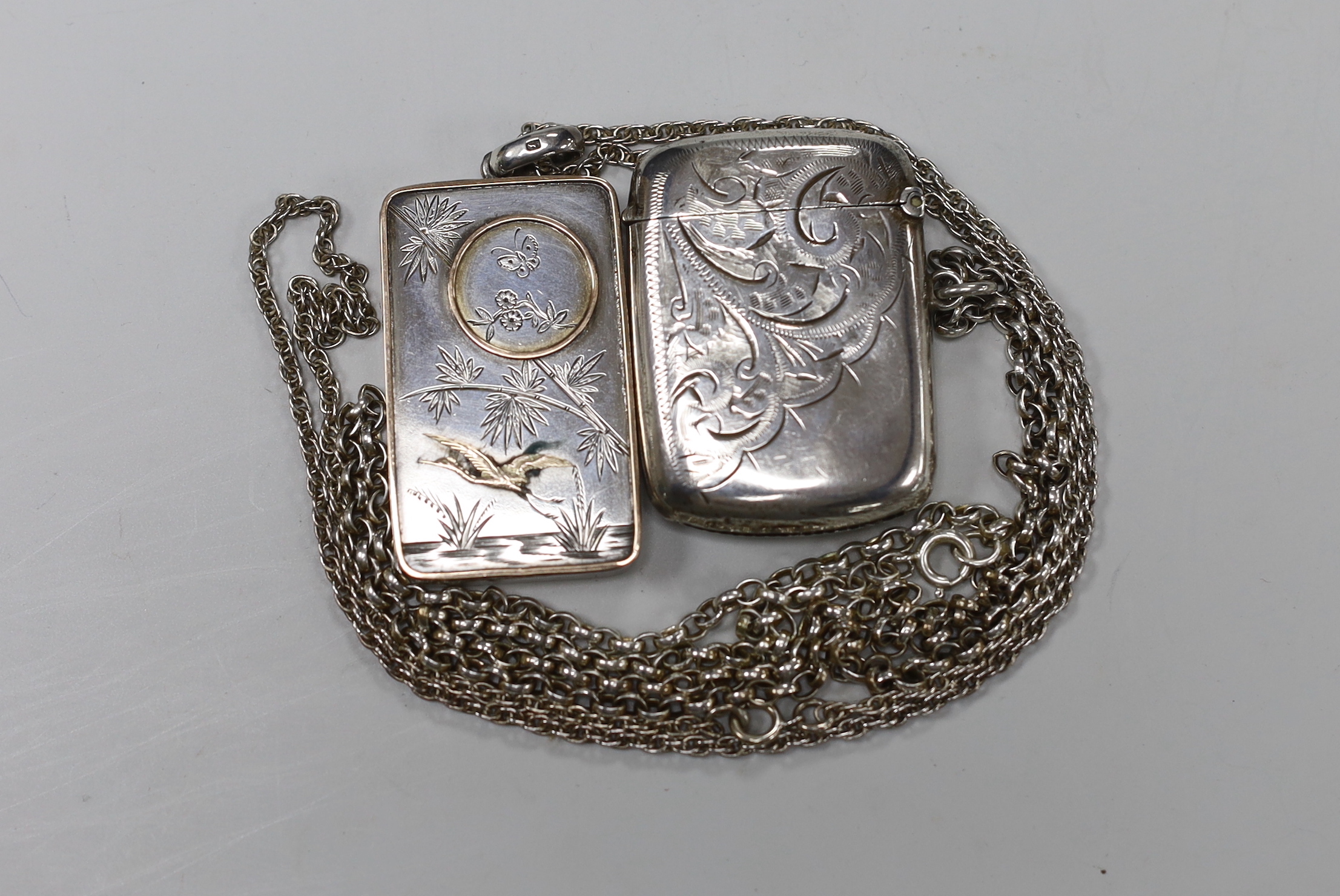 A Japanese parcel gilt white metal rectangular locket (interior crack), 46mm, on a white metal chain and a George V silver vesta case, on a sterling chain.                                                                 