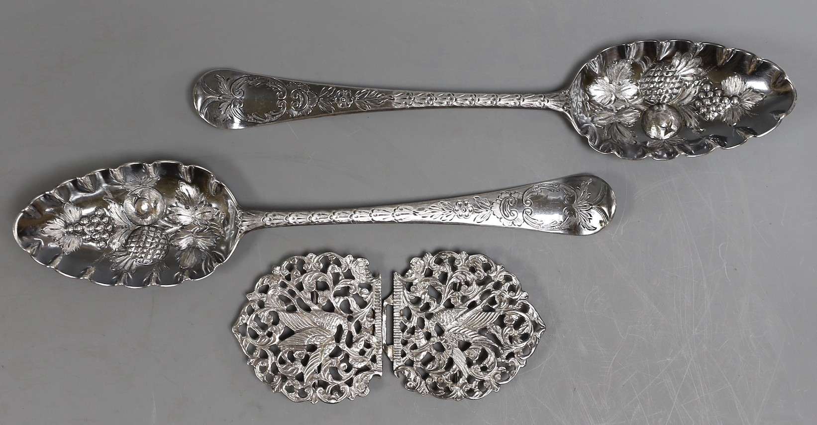 A pair of George III silver Hanovarian pattern 'berry' spoons, Jacob Marsh?, London, 1768, 20.5cm, together with an Edwardian pierced silver nurses buckle, Chester, 1907, decorated with herons, width 10.5cm.             