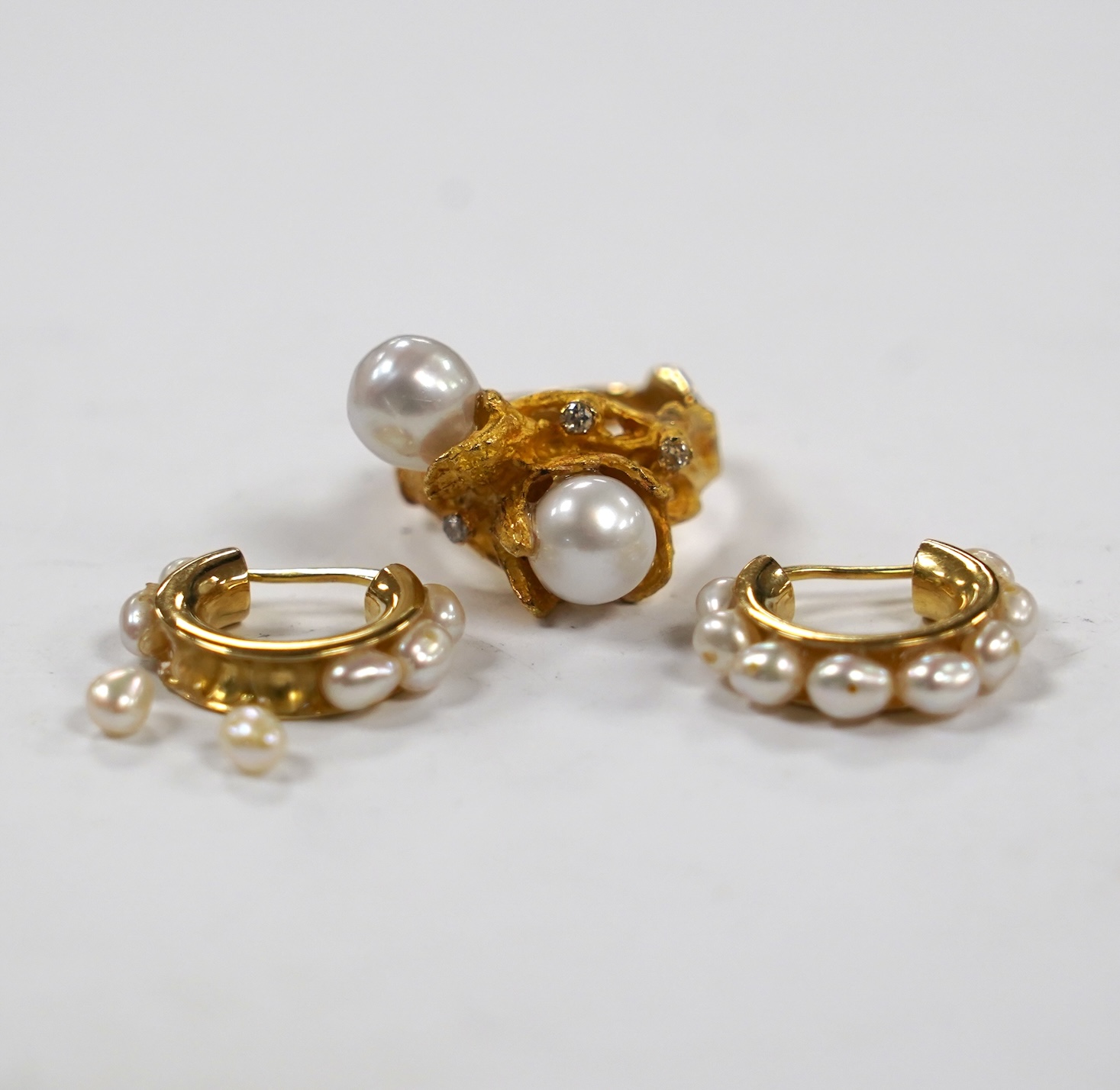 A recent 750 yellow metal two stone cultured pearl and three stone diamond chip set modernist ring, size M/N, gross 9.7 grams and a pair of baroque pearl set half hoop earrings (a.f.).                                    
