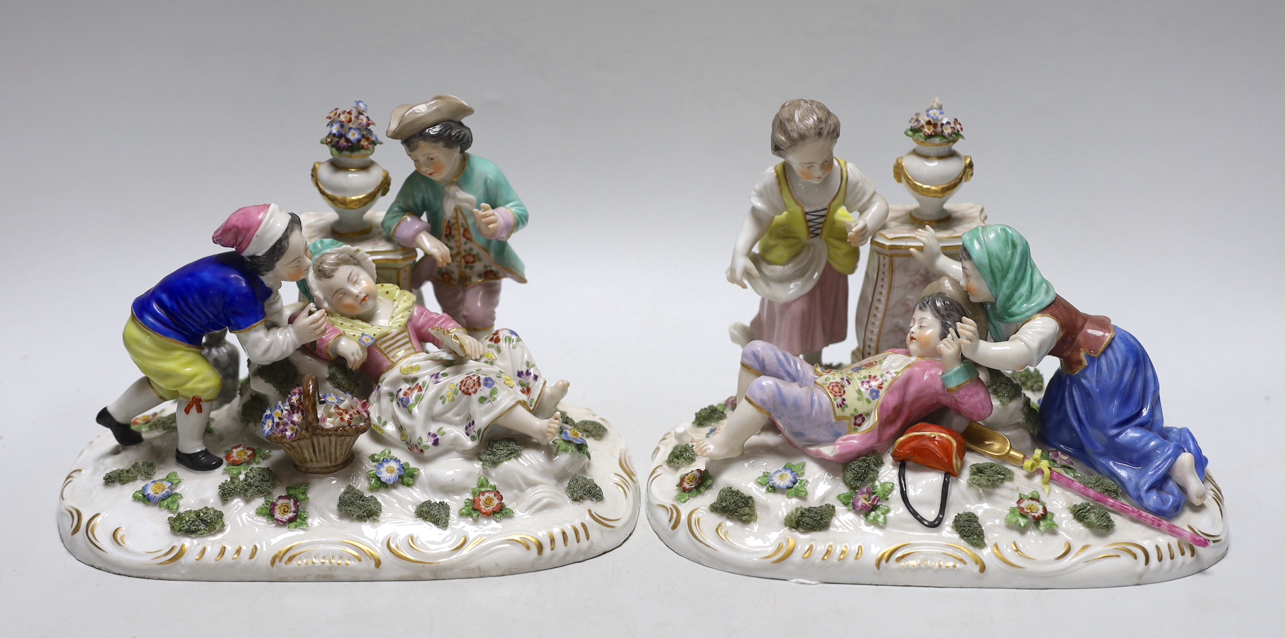 A pair of German porcelain figure groups of children wearing 18th century dress, each with floral encrusted decoration, each 22cm wide                                                                                      