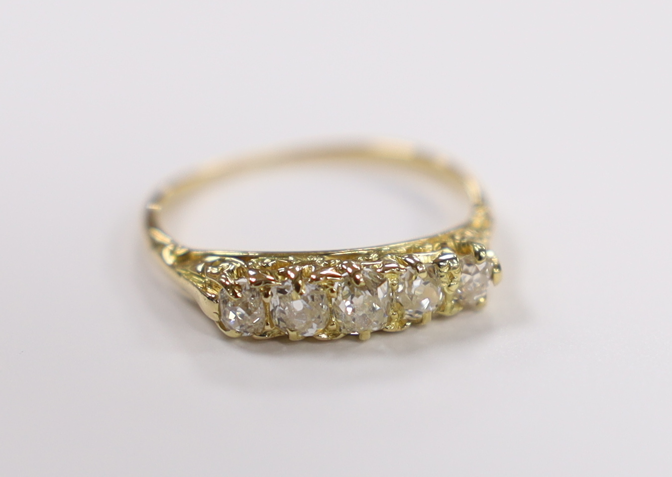 An early 20th century yellow metal and graduated five stone old round diamond set half hoop ring, size M, gross weight 2 grams.                                                                                             