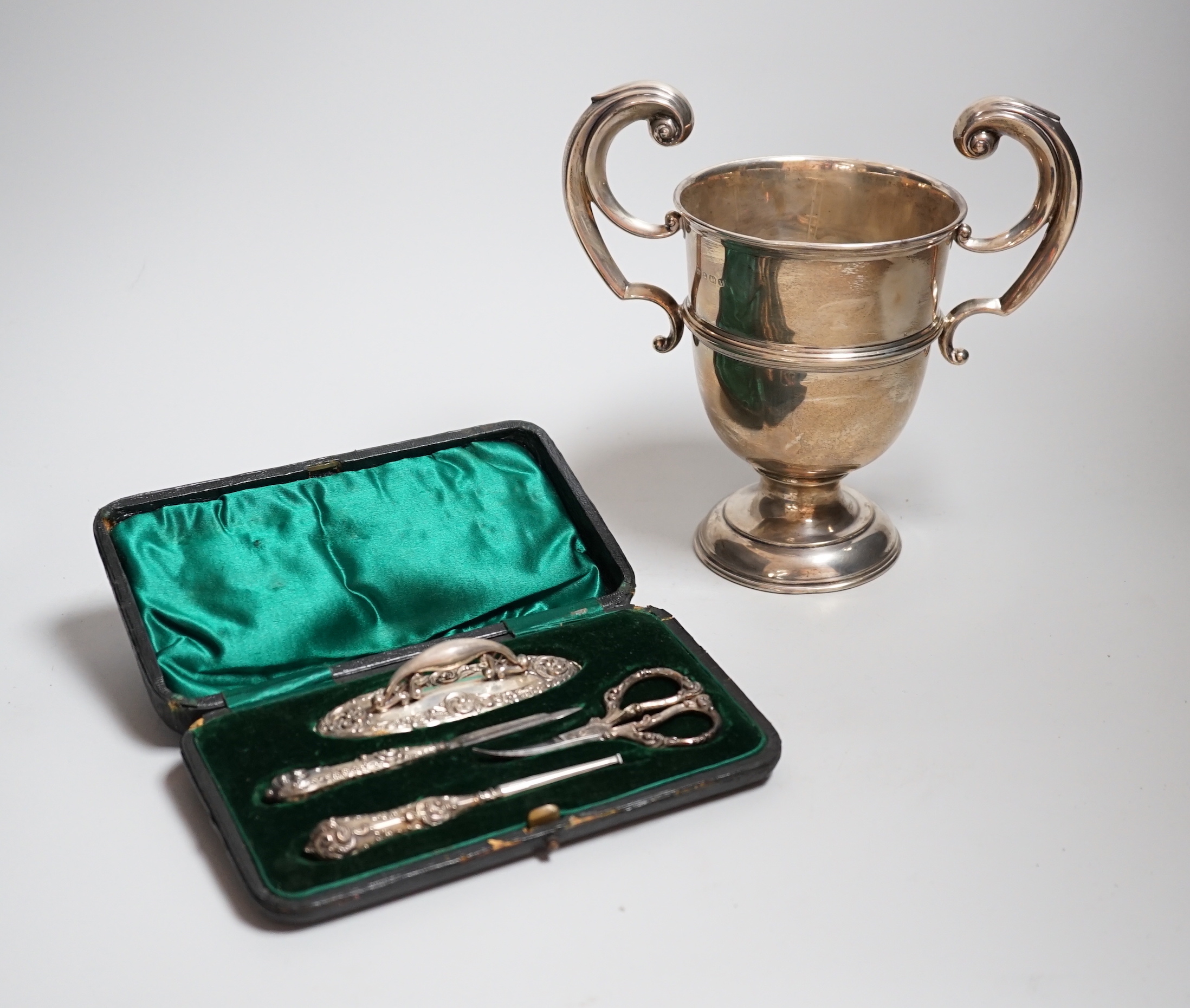 A George V silver two handled presentation cup, William Neale & Sons, Birmingham, 1920, 19.2cm, 9.2oz and a cased silver mounted necessaire set.                                                                            