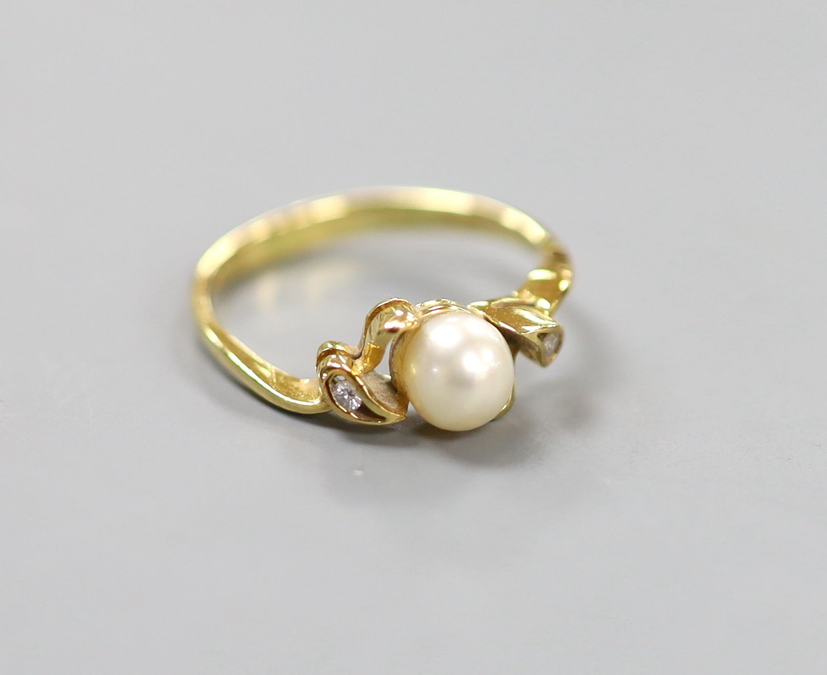 An 18k, single stone cultured pearl and two stone diamond chip set ring, size J, gross 1.9 grams.                                                                                                                           