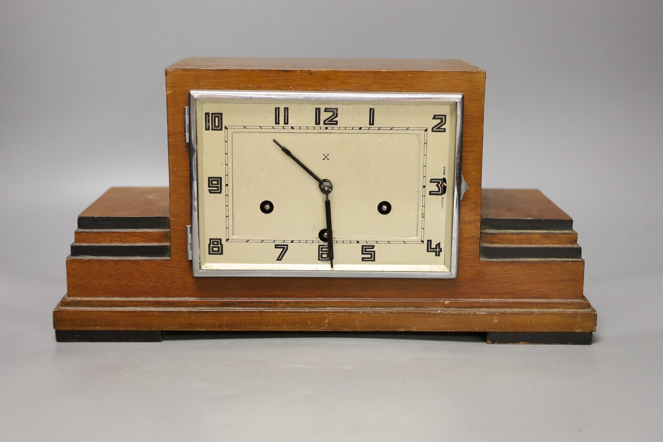 An Art Deco walnut mantel clock, 38 cms wide.                                                                                                                                                                               