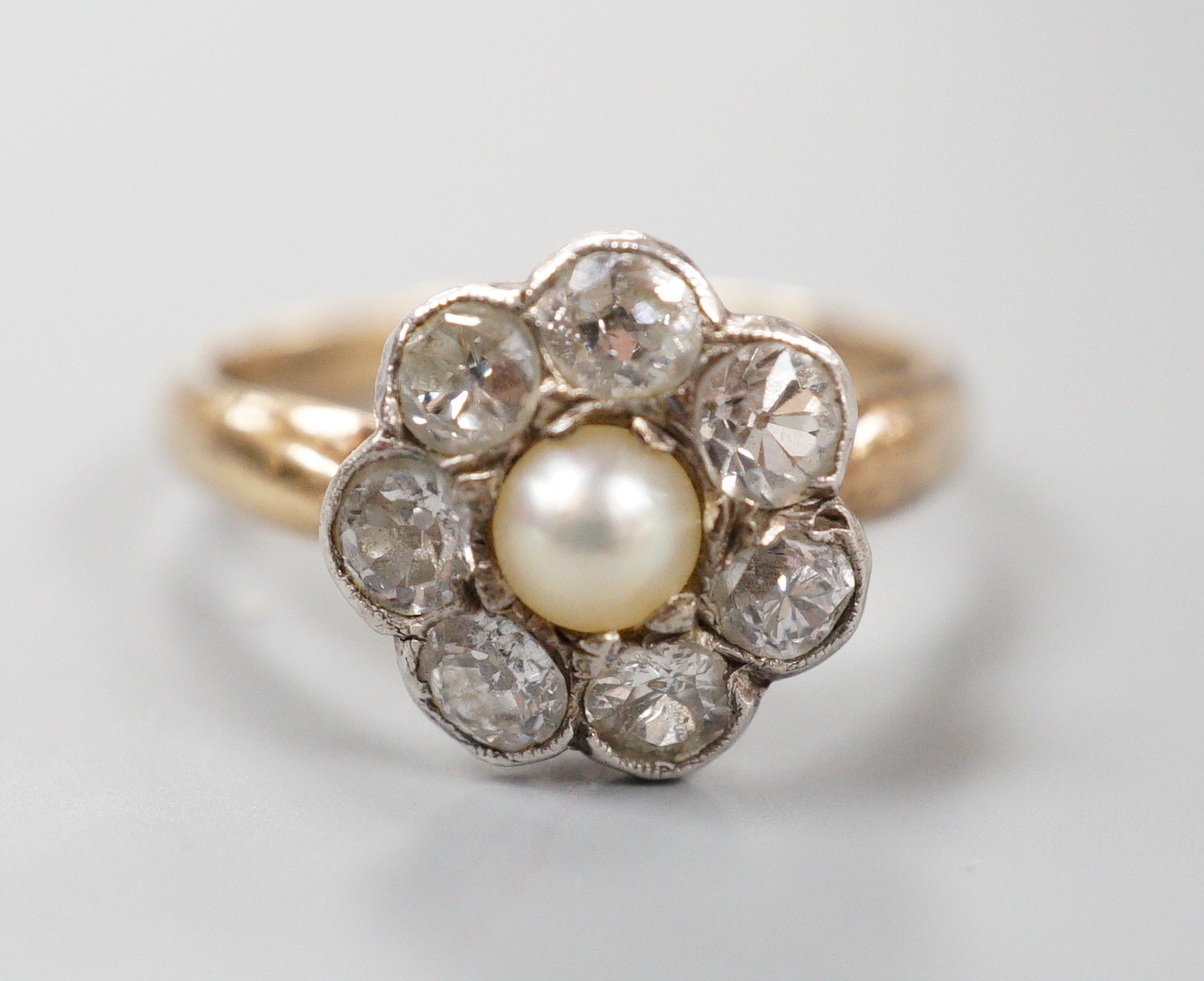 A late Victorian yellow metal, single stone split pearl and seven stone diamond set circular cluster ring, size I, gross weight 3 grams.                                                                                    