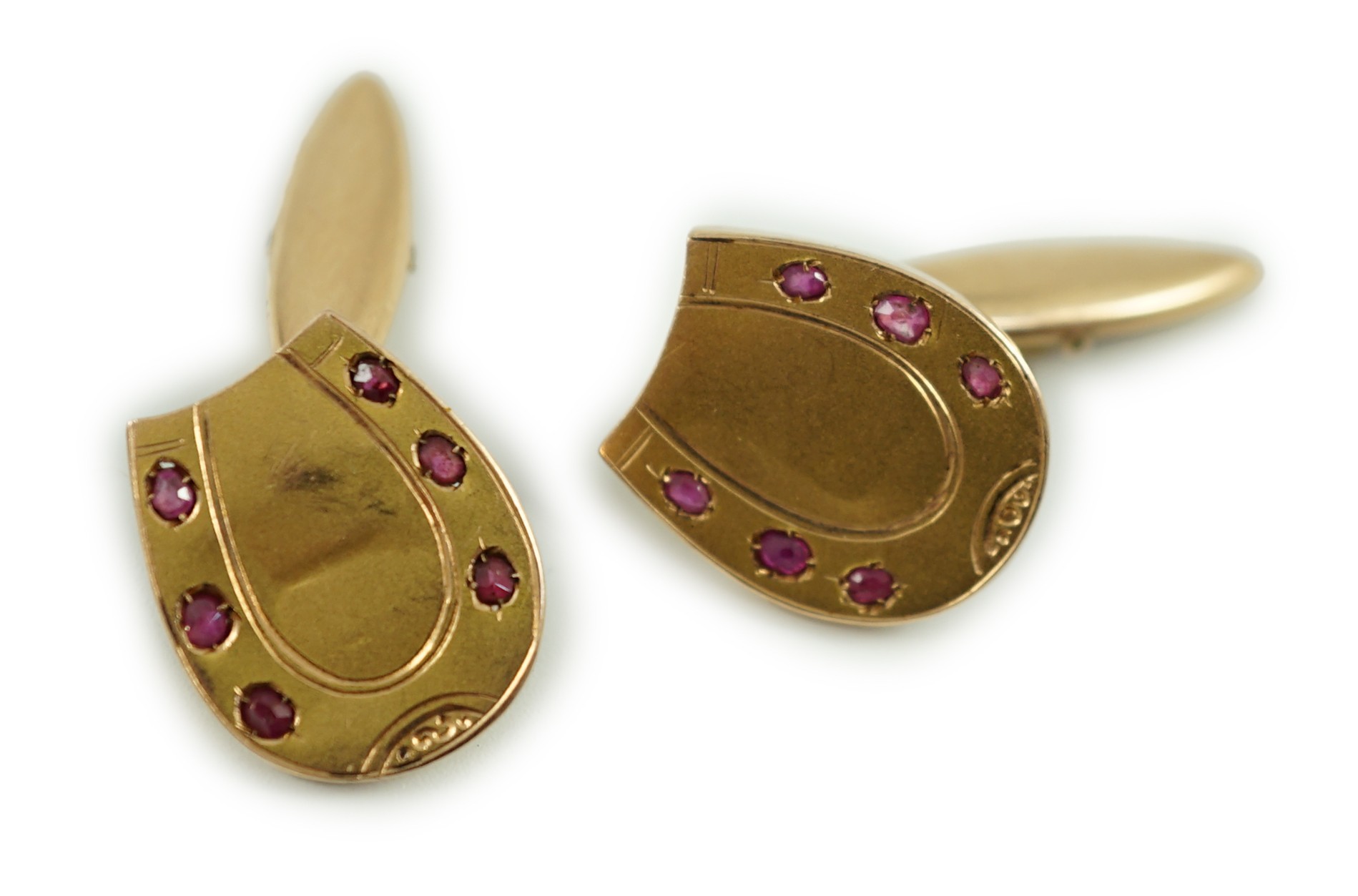 A pair of early 20th century Russian 56 zolotnik yellow metal and ruby set horseshoe shaped cufflinks, 16mm, gross weight 3.9 grams.                                                                                        