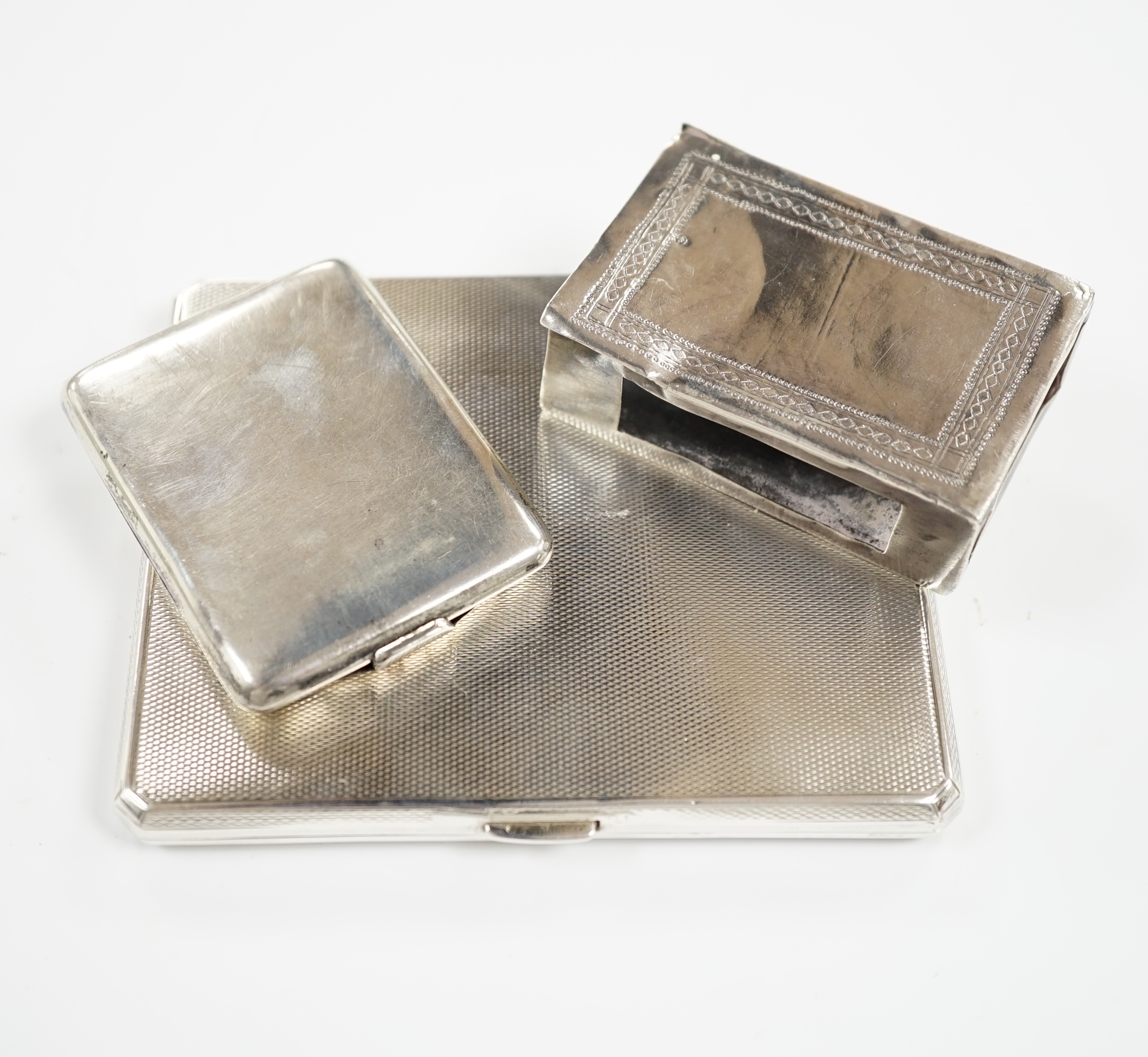 A George V engine turned silver cigarette case, Walker & Hall, London, 1935, 10.2cm and two matchbox holders, one silver.                                                                                                   