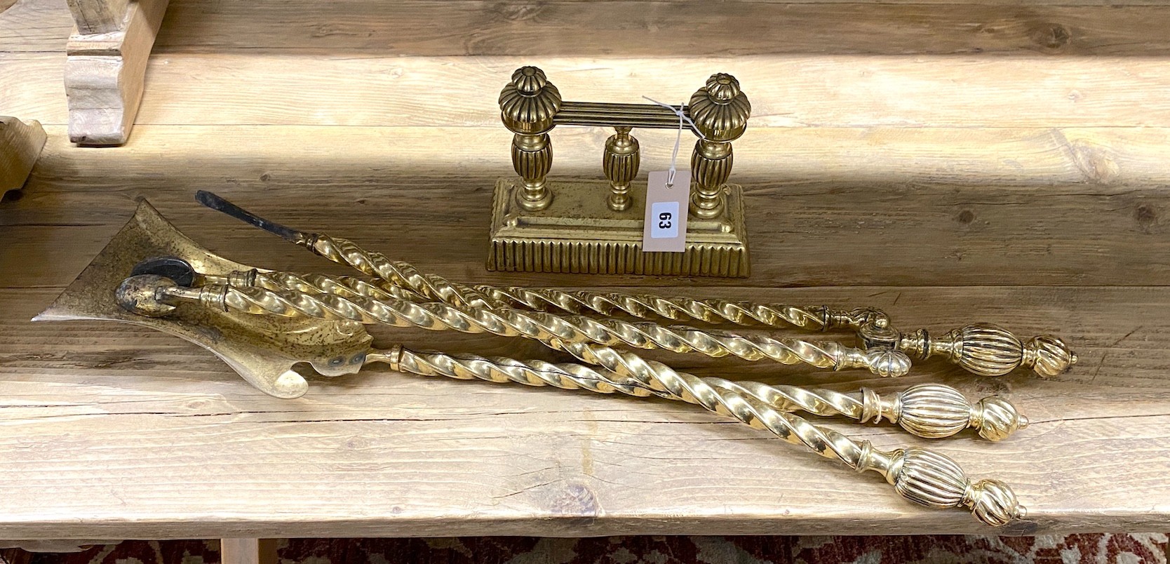 A set of three Edwardian brass fire implements and a fire dog                                                                                                                                                               